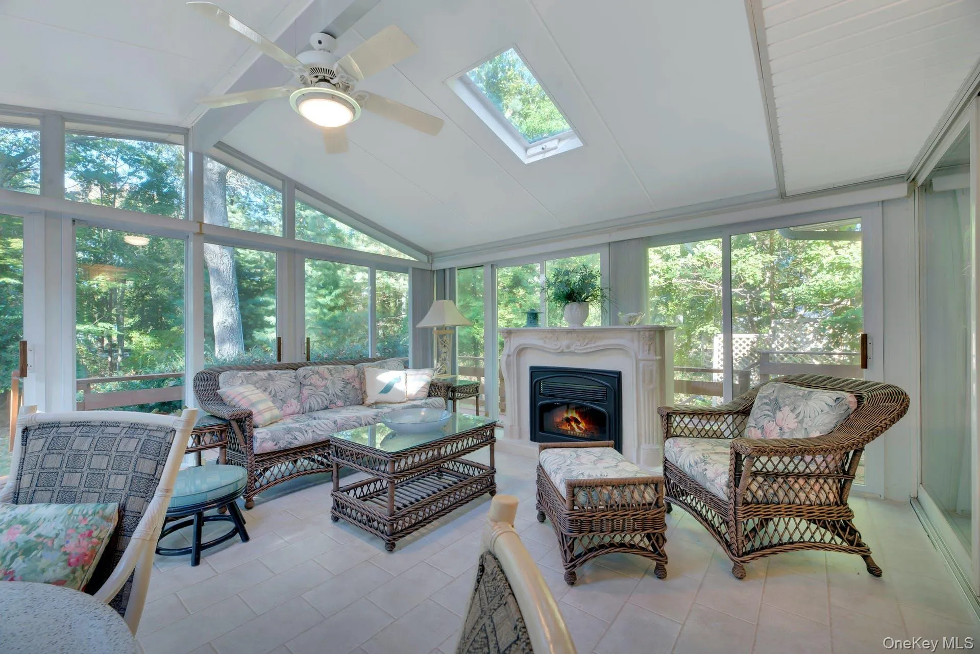 Sunroom / solarium featuring a ceiling fan, lofted ceiling, an outdoor living space with a fireplace, and a skylight Sunroom / solarium featuring a ceiling fan, lofted ceiling, an outdoor living space with a fireplace, and a skylight