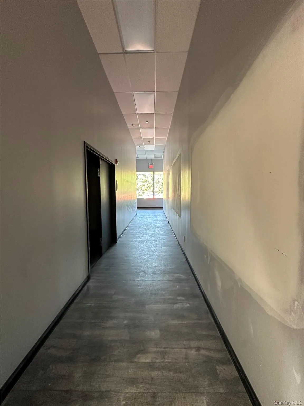 Hall with a drop ceiling and dark wood finished floors Hall with a drop ceiling and dark wood finished floors