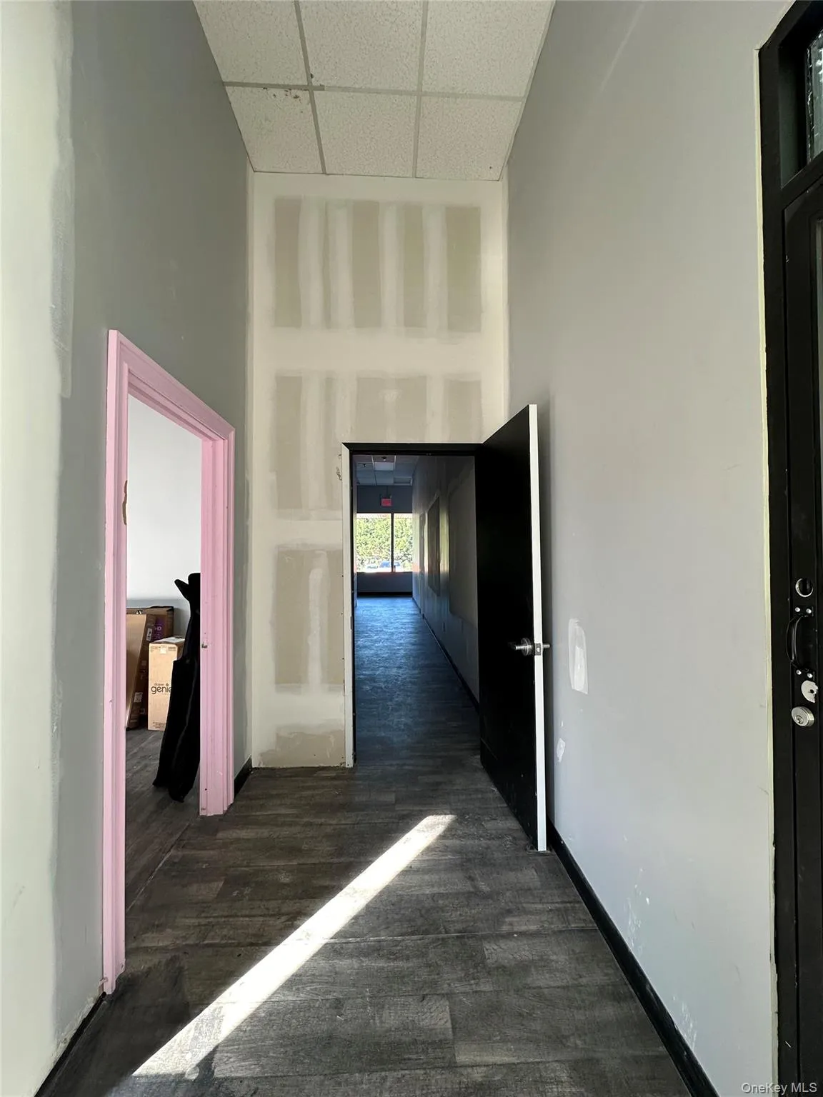 Hallway featuring a towering ceiling, a drop ceiling, and dark wood finished floors Hallway featuring a towering ceiling, a drop ceiling, and dark wood finished floors
