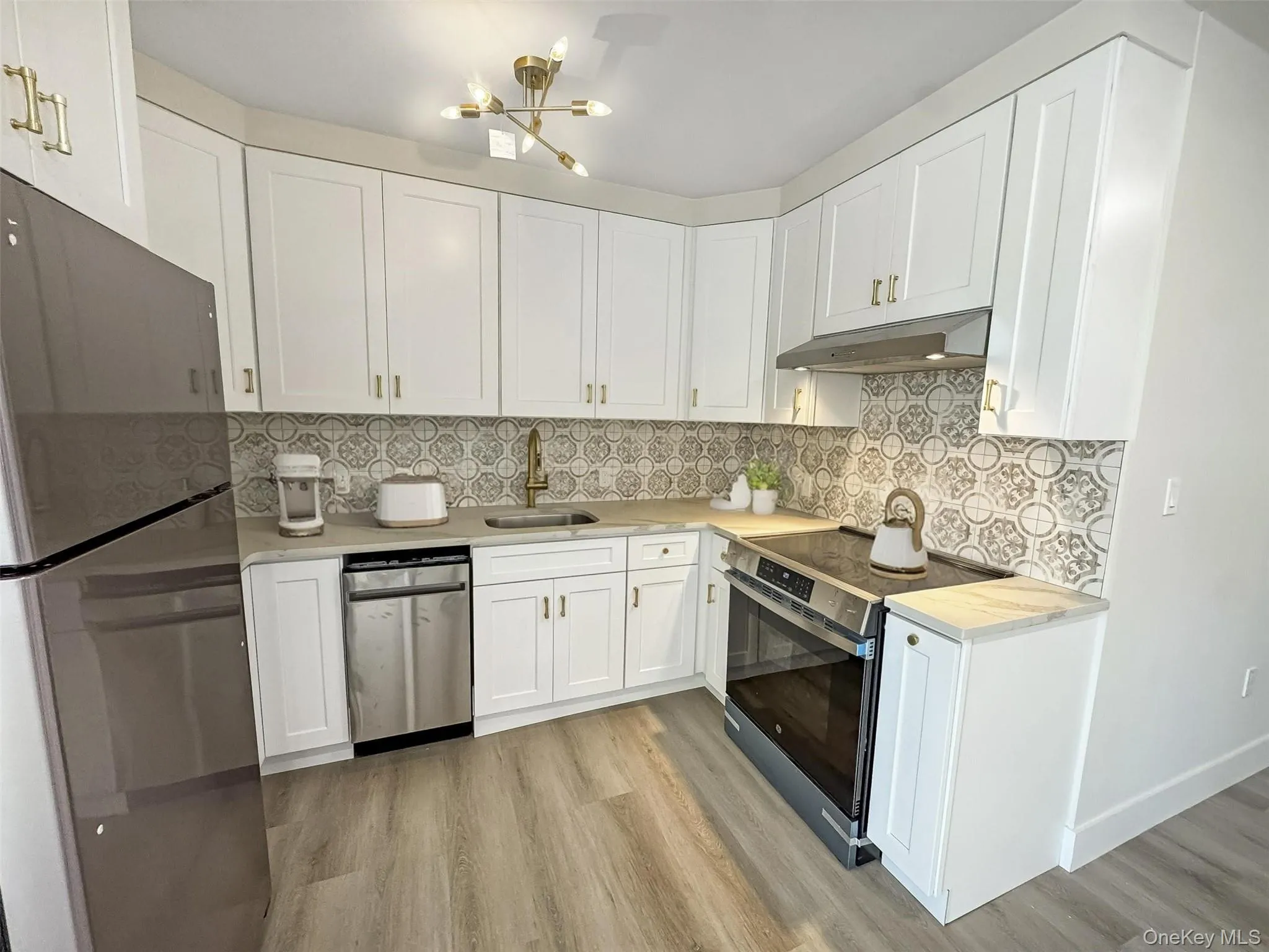 Kitchen featuring appliances with stainless steel finishes, white cabinets, and light wood finished floors Kitchen featuring appliances with stainless steel finishes, white cabinets, and light wood finished floors