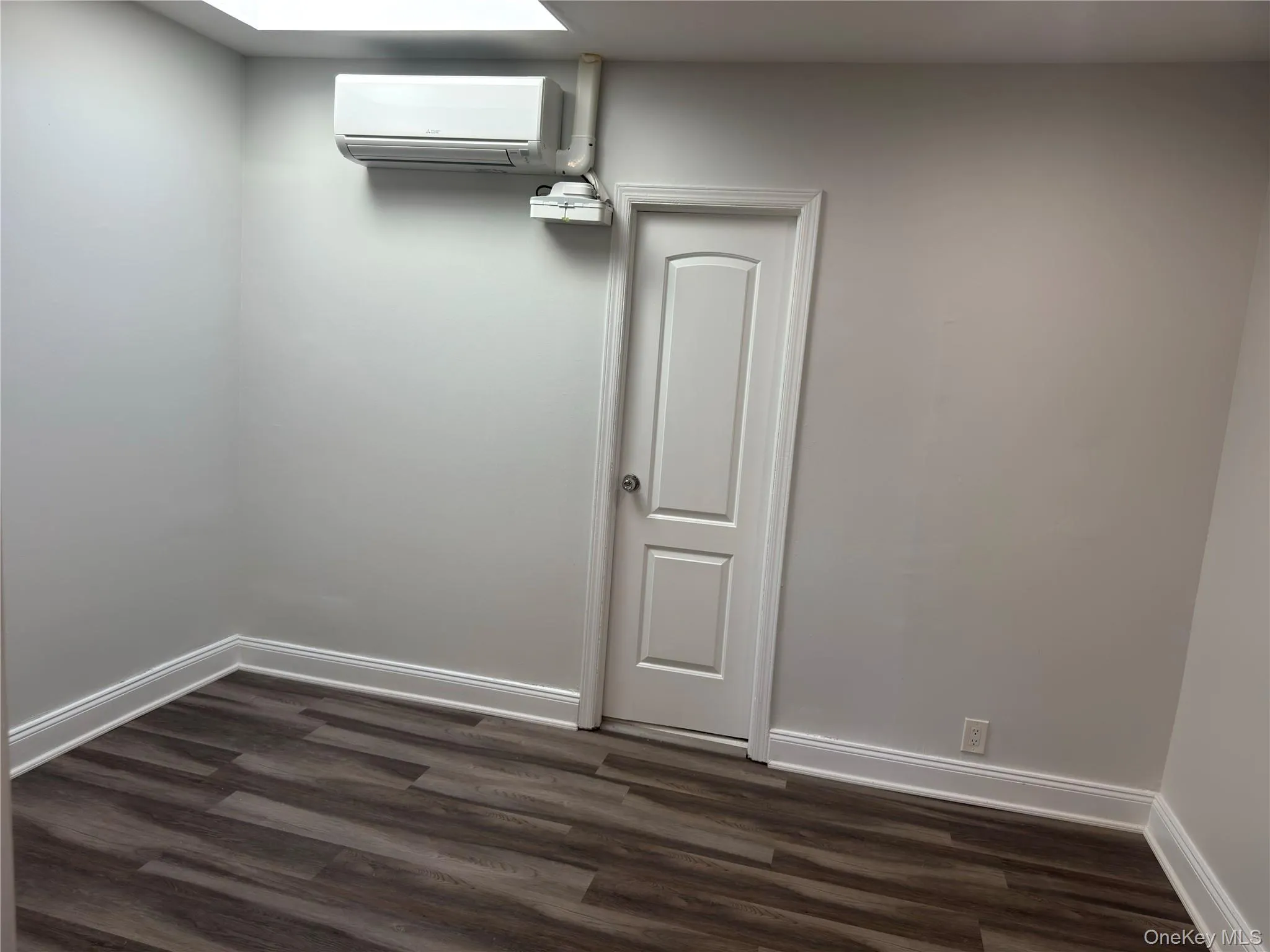 Spare room featuring a wall unit AC and dark wood-type flooring Spare room featuring a wall unit AC and dark wood-type flooring
