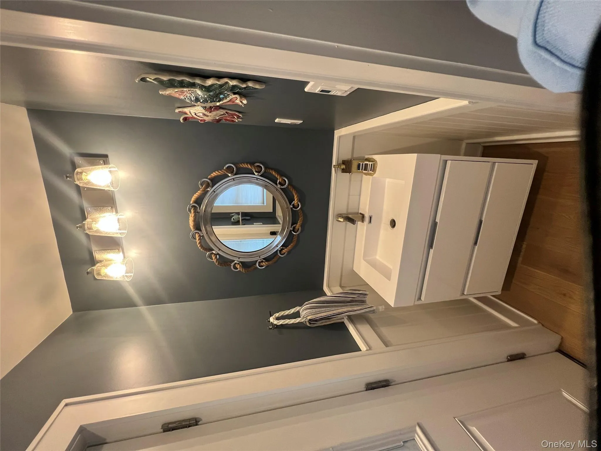 Bathroom with wainscoting, vanity, dark wood-type flooring, and a decorative wall Bathroom with wainscoting, vanity, dark wood-type flooring, and a decorative wall