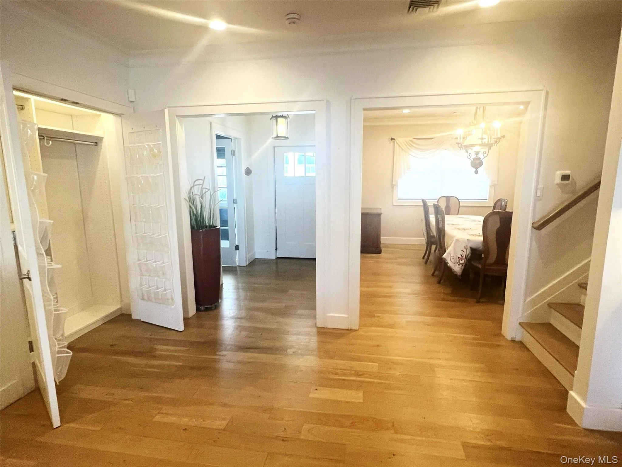 Hallway with light wood finished floors, stairs, a chandelier, ornamental molding, and recessed lighting Hallway with light wood finished floors, stairs, a chandelier, ornamental molding, and recessed lighting