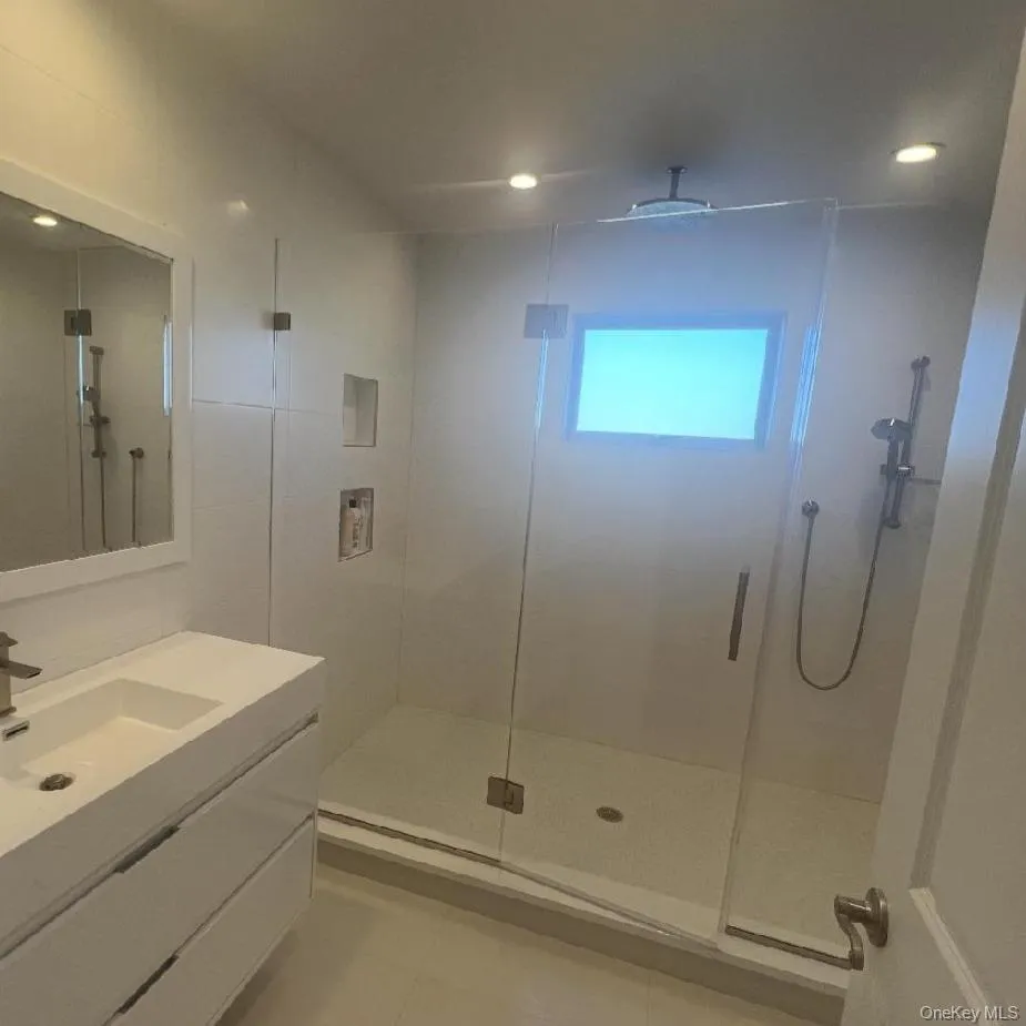 Full bath with vanity, a stall shower, and light tile patterned floors Full bath with vanity, a stall shower, and light tile patterned floors