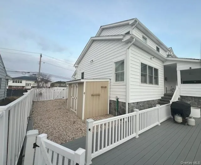 View of property exterior with a wooden deck, a storage shed, and a fenced backyard View of property exterior with a wooden deck, a storage shed, and a fenced backyard