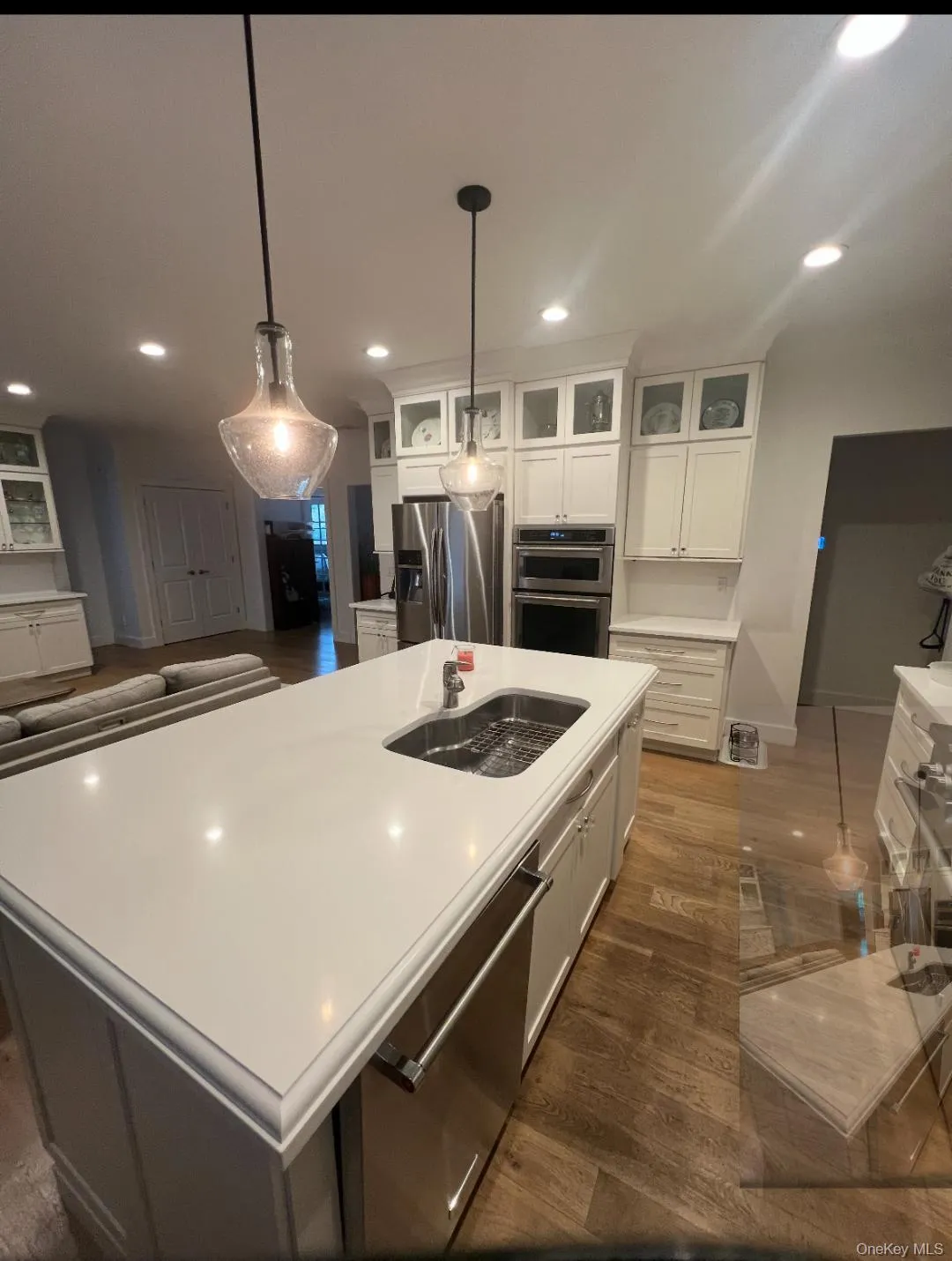 Kitchen with dark wood-style floors, glass insert cabinets, appliances with stainless steel finishes, hanging light fixtures, and recessed lighting Kitchen with dark wood-style floors, glass insert cabinets, appliances with stainless steel finishes, hanging light fixtures, and recessed lighting