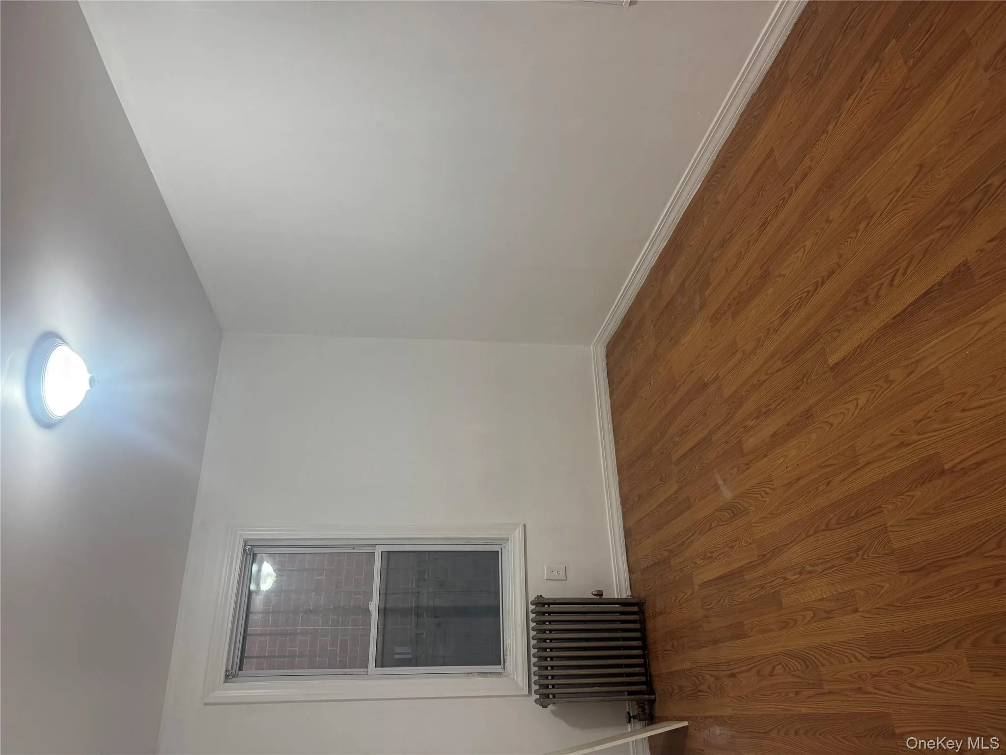 Empty room featuring radiator heating unit and wood finished floors Empty room featuring radiator heating unit and wood finished floors