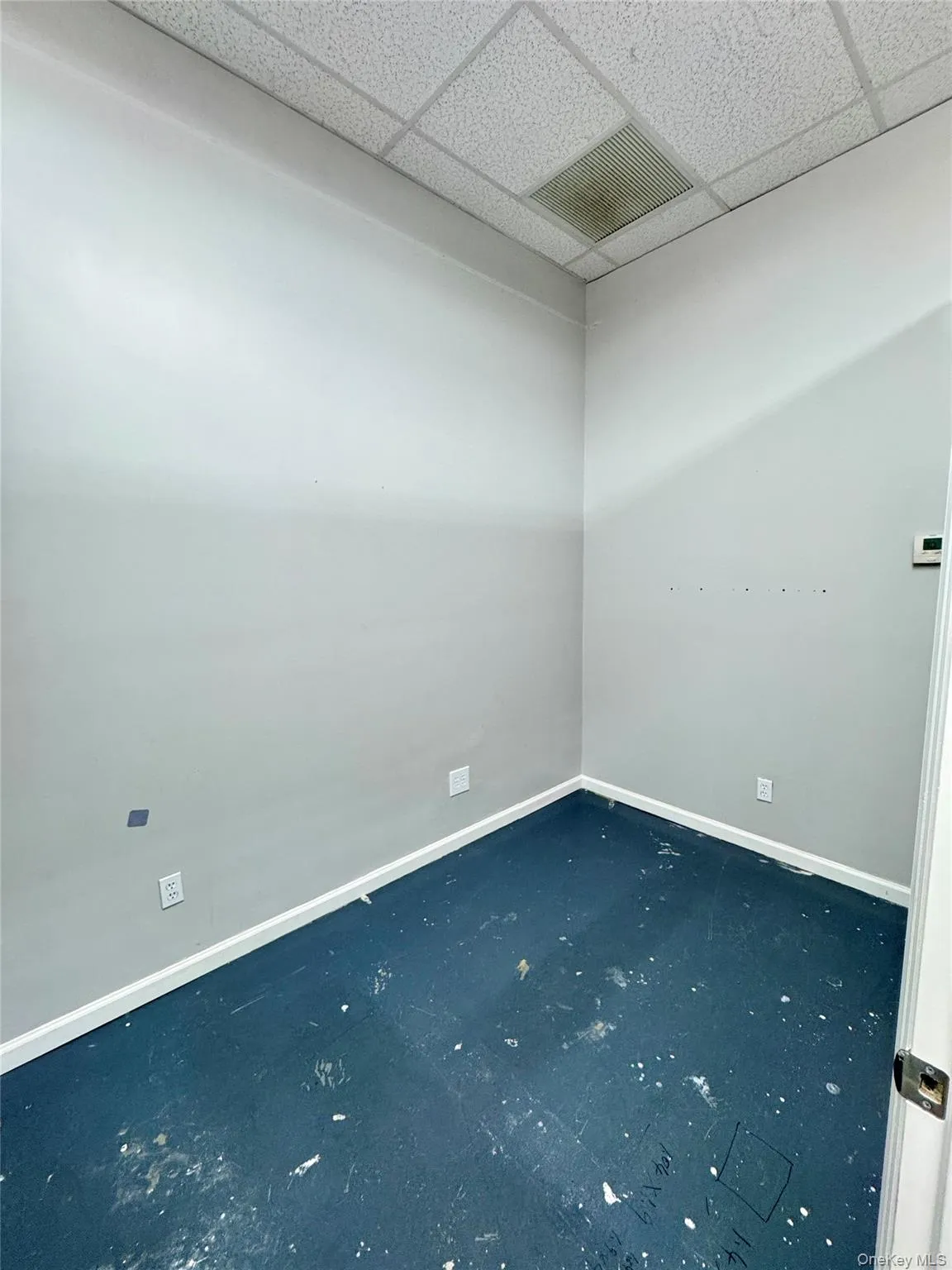 Unfurnished room with baseboards and a drop ceiling Unfurnished room with baseboards and a drop ceiling