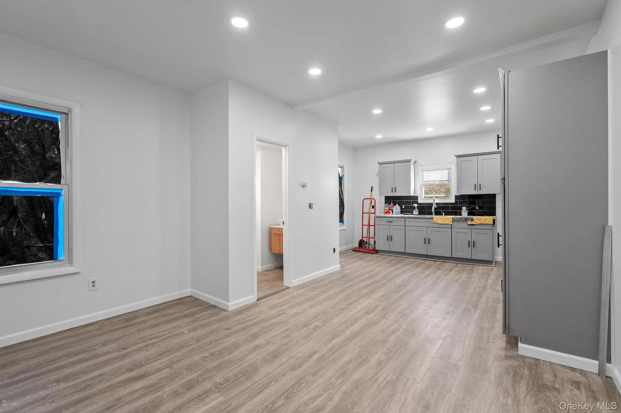Kitchen featuring gray cabinetry, recessed lighting, light wood-type flooring, backsplash, and light countertops Kitchen featuring gray cabinetry, recessed lighting, light wood-type flooring, backsplash, and light countertops