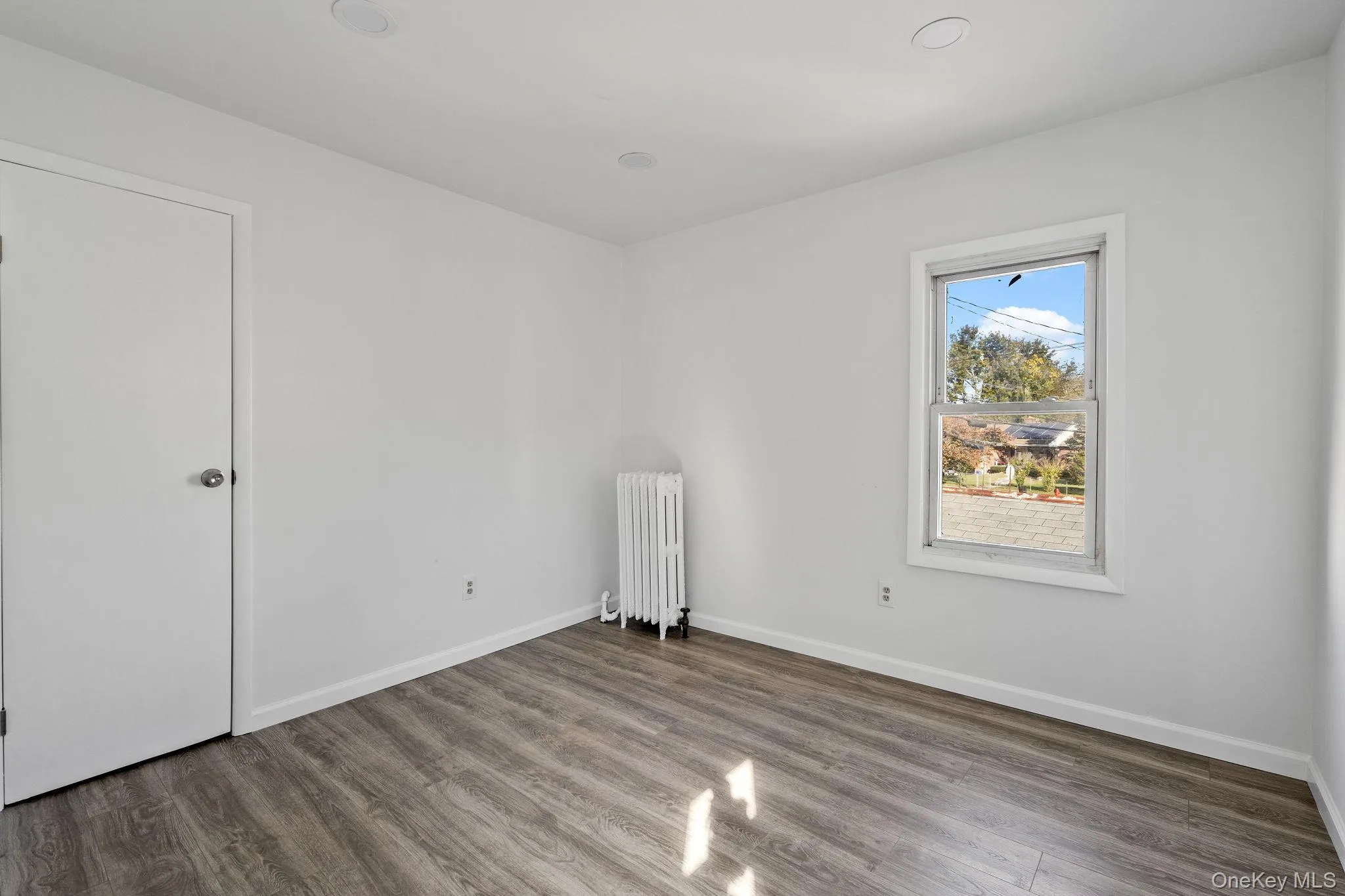 Unfurnished room with radiator heating unit and wood finished floors Unfurnished room with radiator heating unit and wood finished floors