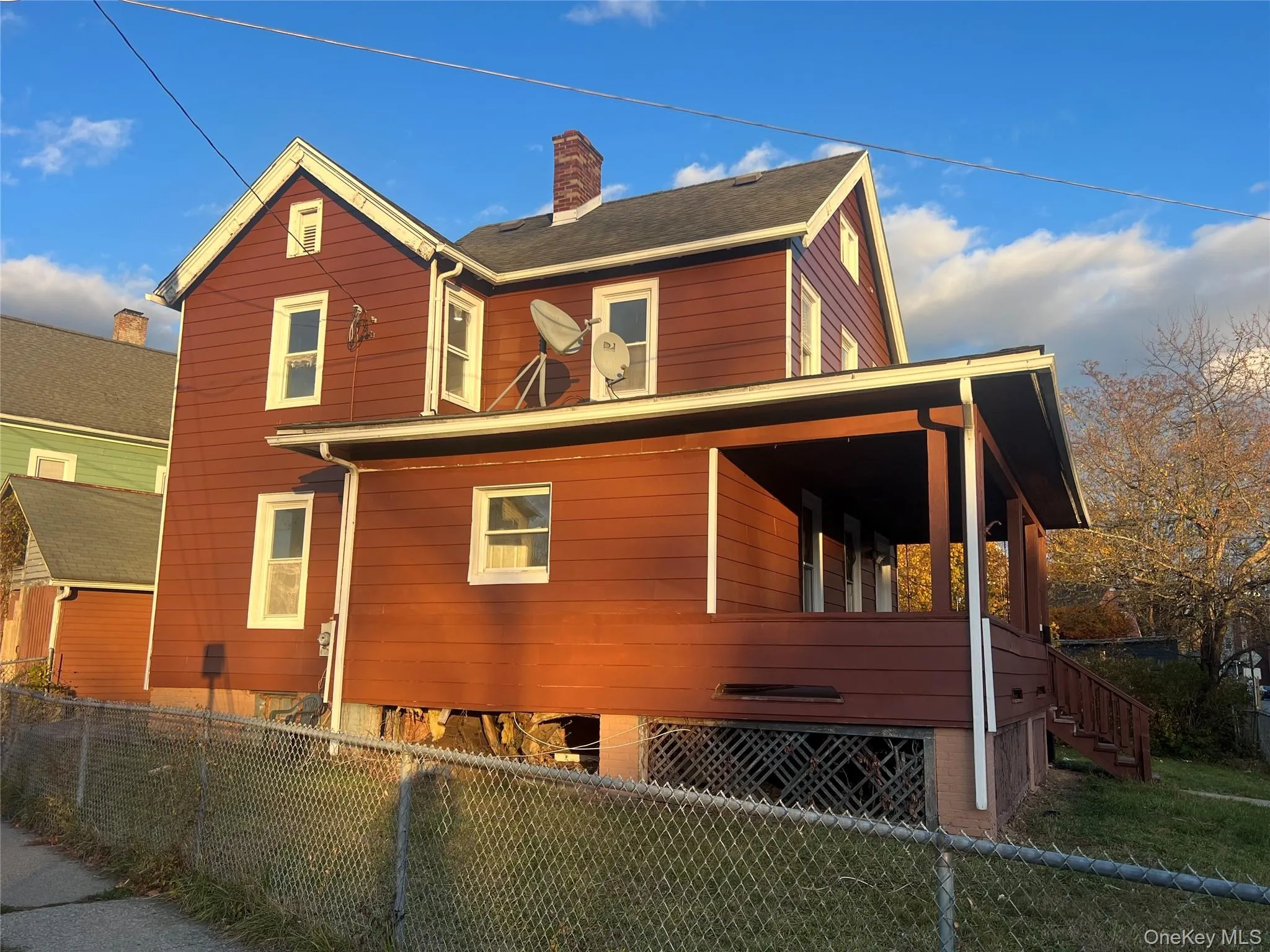 View of side of property featuring a fenced backyard, covered porch, stairway, and a chimney View of side of property featuring a fenced backyard, covered porch, stairway, and a chimney
