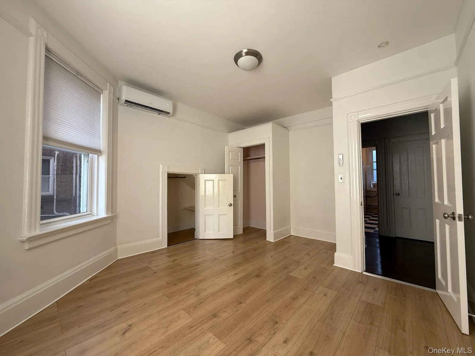 Unfurnished bedroom featuring light wood-style floors, a closet, and a wall mounted air conditioner Unfurnished bedroom featuring light wood-style floors, a closet, and a wall mounted air conditioner