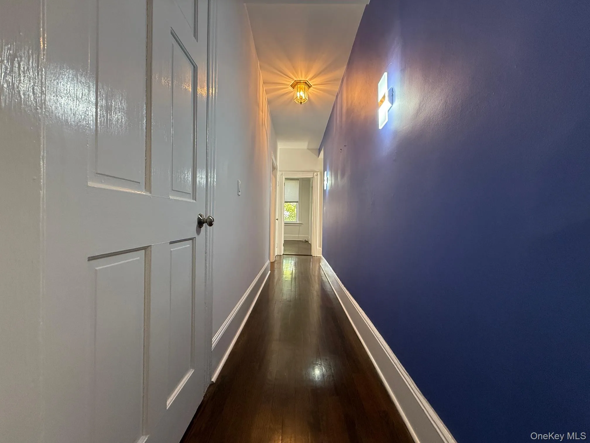 Hallway featuring dark wood-style flooring and baseboards Hallway featuring dark wood-style flooring and baseboards