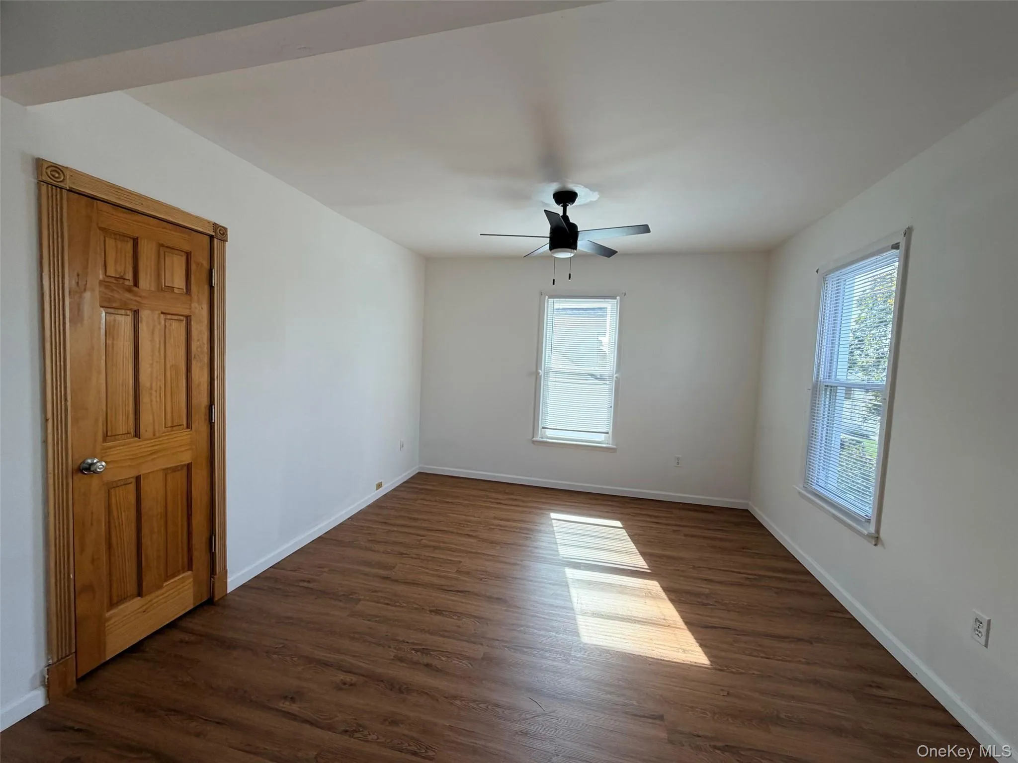Unfurnished room with dark wood-style floors, plenty of natural light, and a ceiling fan Unfurnished room with dark wood-style floors, plenty of natural light, and a ceiling fan