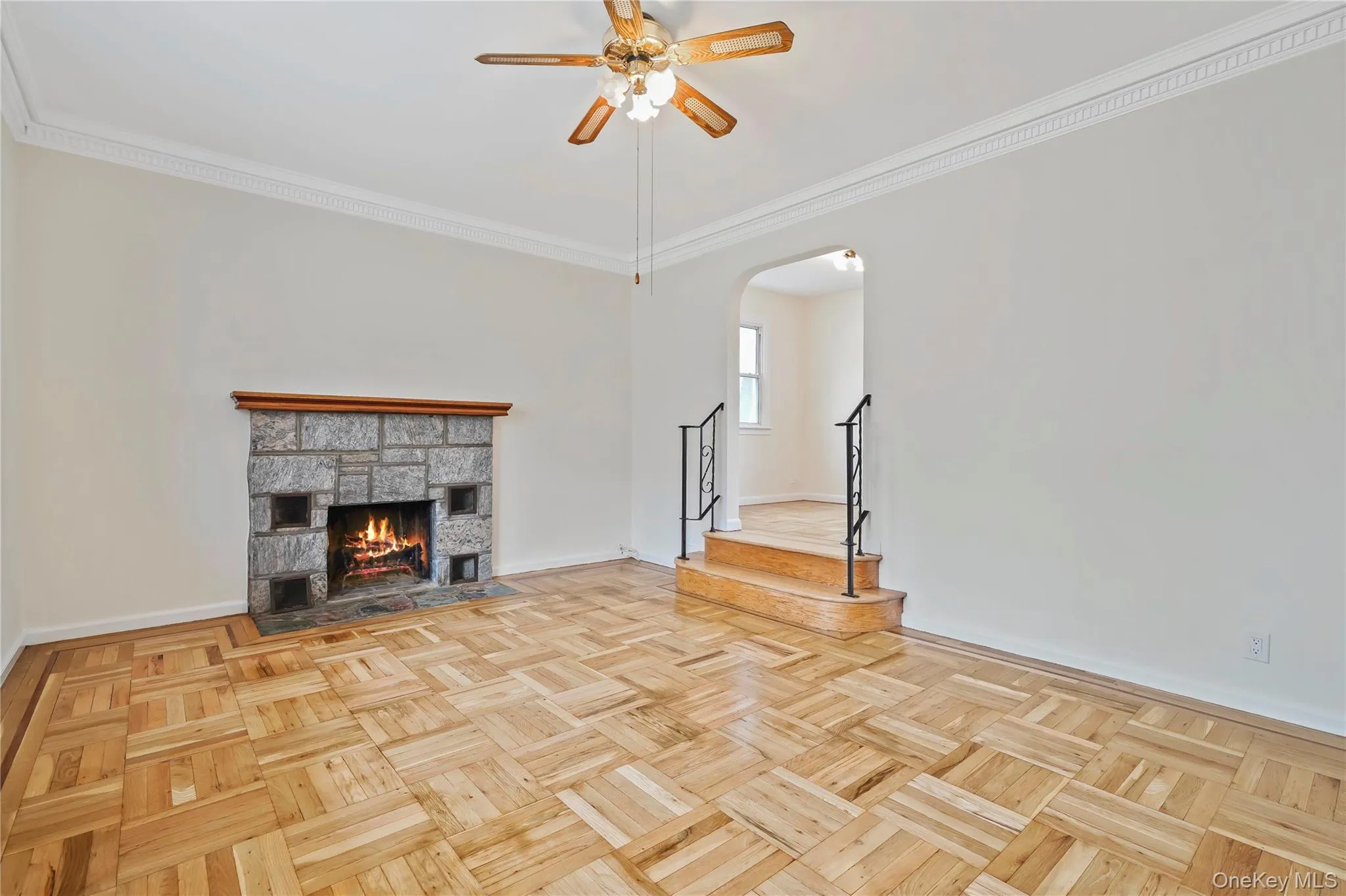 Unfurnished living room with crown molding, stairway, arched walkways, a fireplace, and ceiling fan Unfurnished living room with crown molding, stairway, arched walkways, a fireplace, and ceiling fan