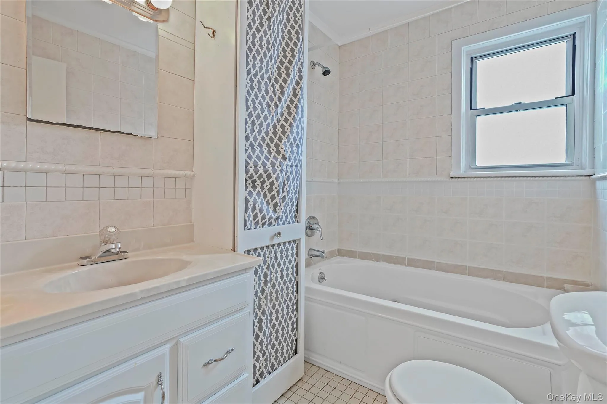 Bathroom with tile walls, vanity, light tile patterned flooring, crown molding, and shower / bath combination Bathroom with tile walls, vanity, light tile patterned flooring, crown molding, and shower / bath combination