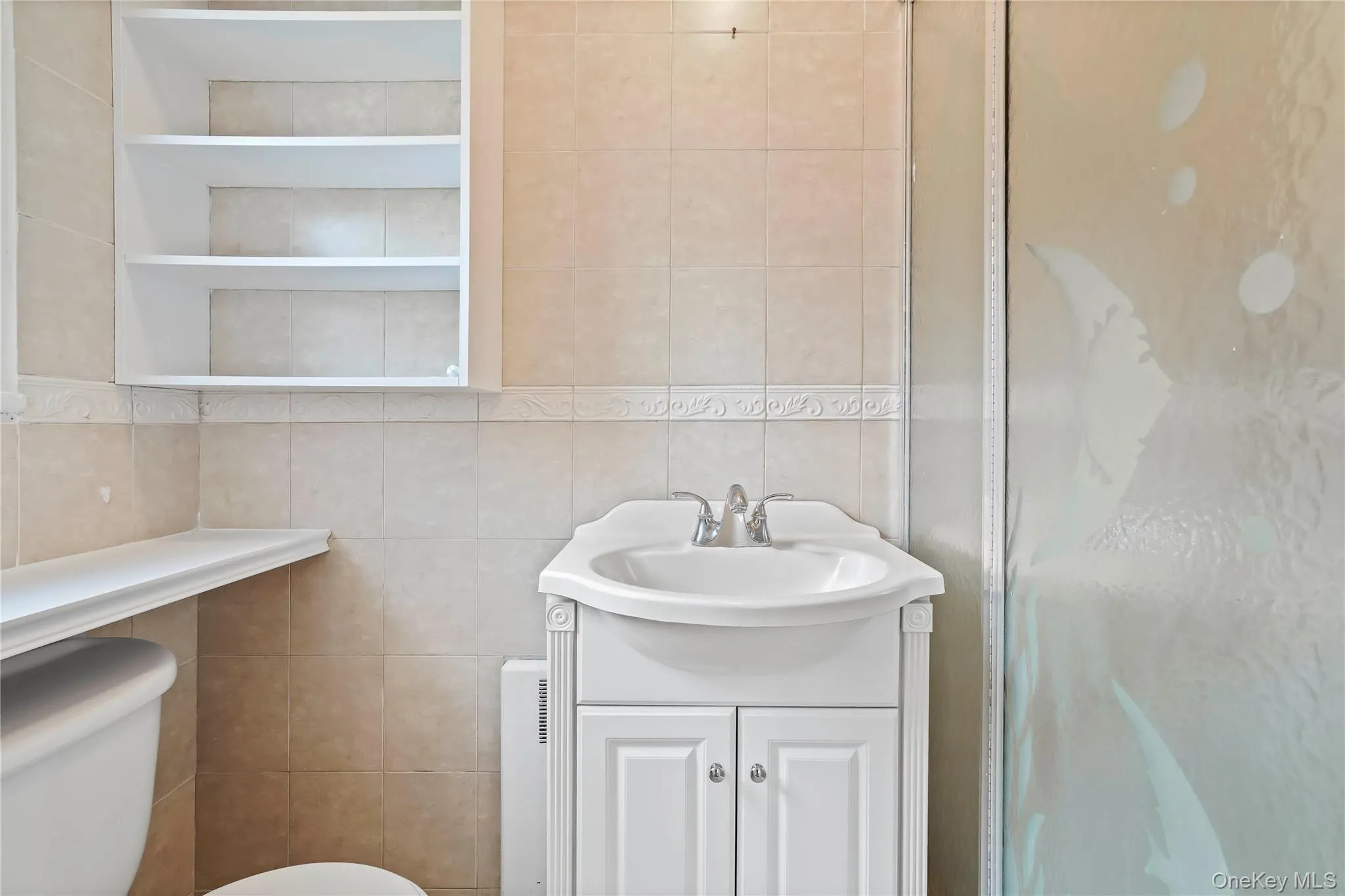 Bathroom with vanity, tile walls, and a shower stall Bathroom with vanity, tile walls, and a shower stall