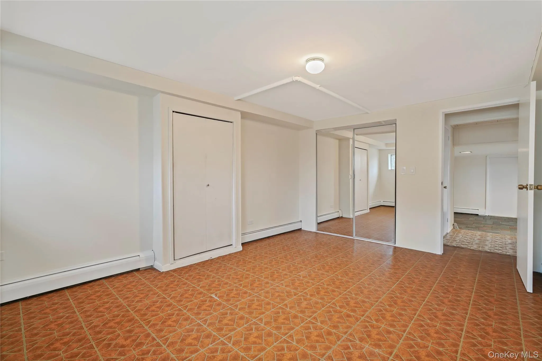 Unfurnished bedroom with baseboard heating and two closets Unfurnished bedroom with baseboard heating and two closets