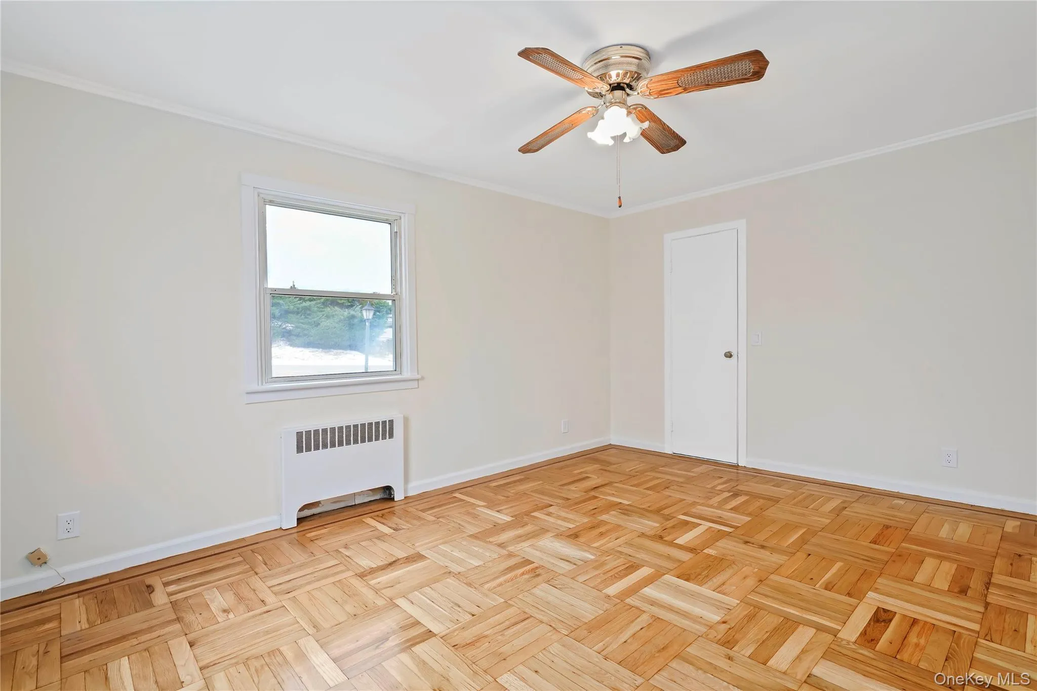 Empty room featuring crown molding, radiator, and a ceiling fan Empty room featuring crown molding, radiator, and a ceiling fan