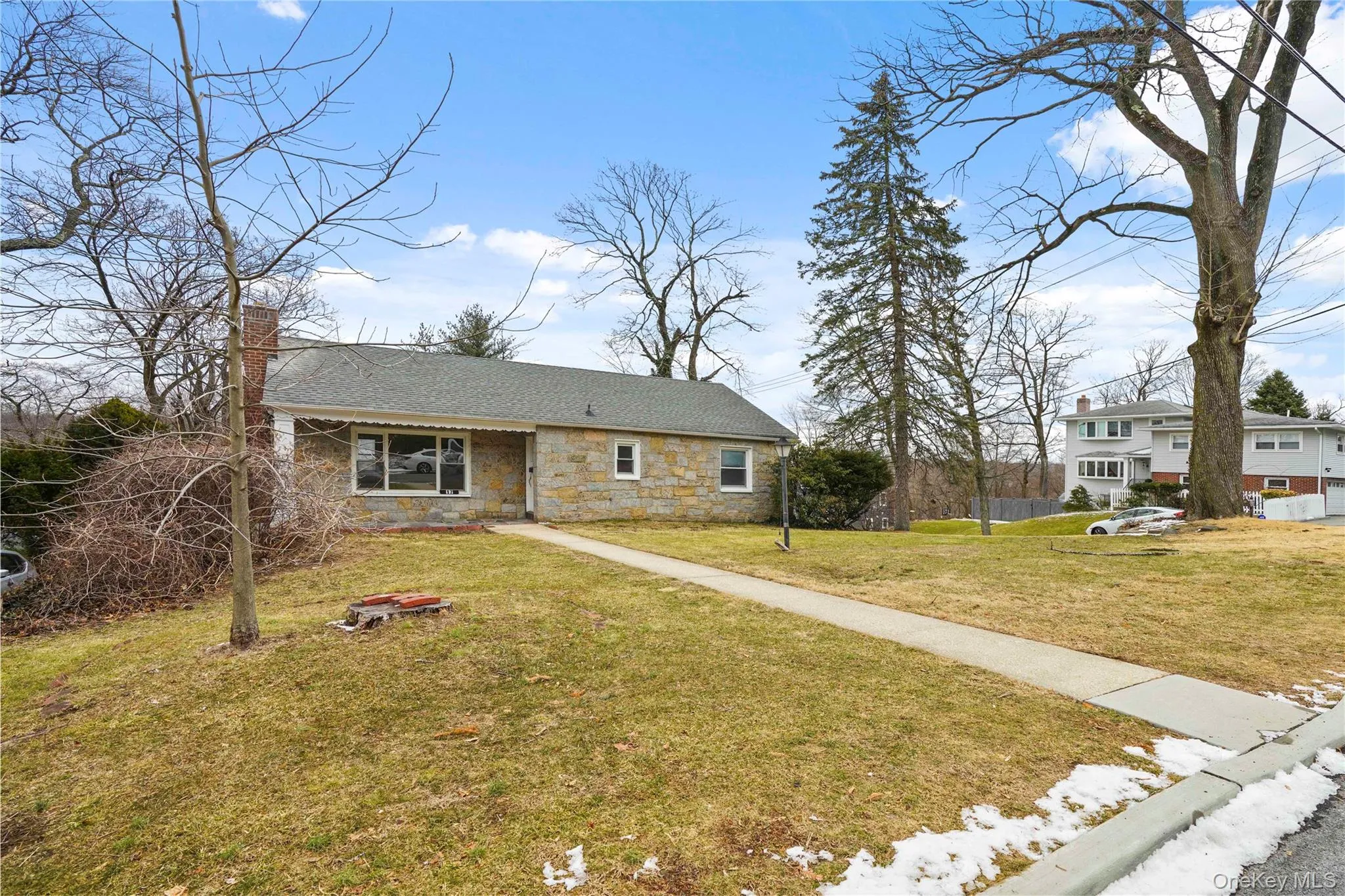 View of front facade with stone siding, a chimney, a front lawn, and a shingled roof View of front facade with stone siding, a chimney, a front lawn, and a shingled roof