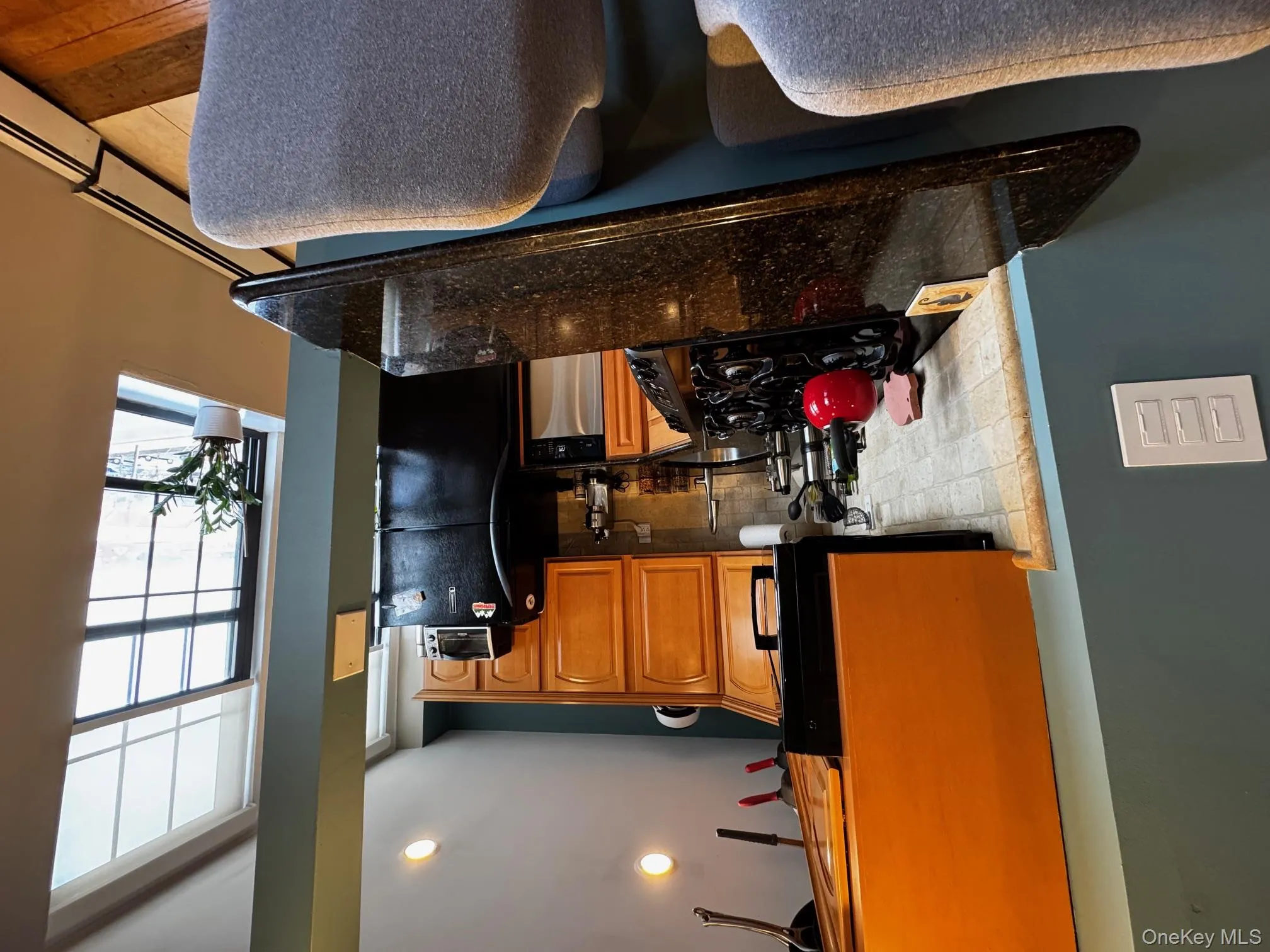 Kitchen with dishwashing machine, stove, fridge, brown cabinets, and dark stone counters Kitchen with dishwashing machine, stove, fridge, brown cabinets, and dark stone counters