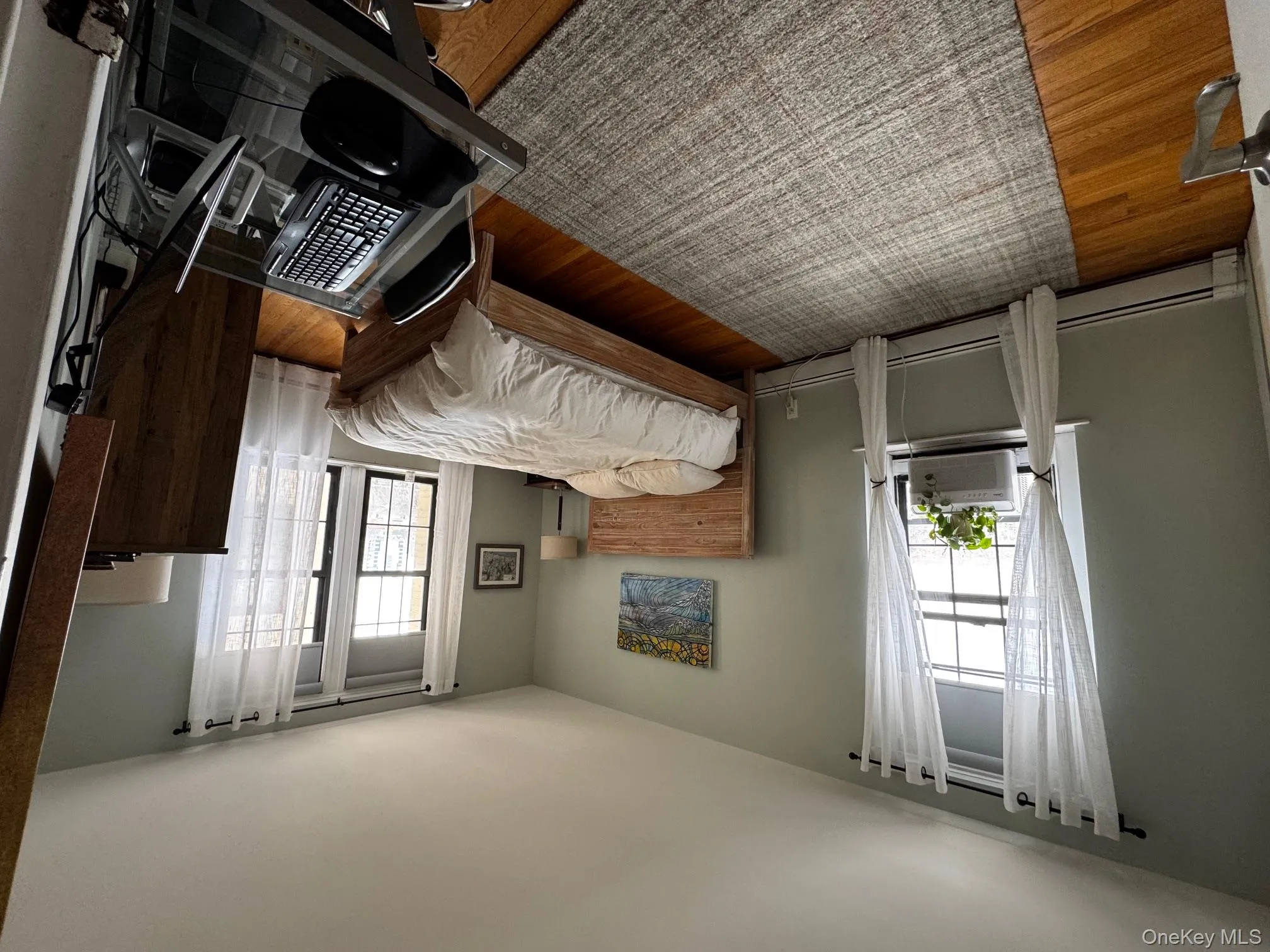 Bedroom featuring a baseboard radiator, cooling unit, baseboards, and wood finished floors Bedroom featuring a baseboard radiator, cooling unit, baseboards, and wood finished floors