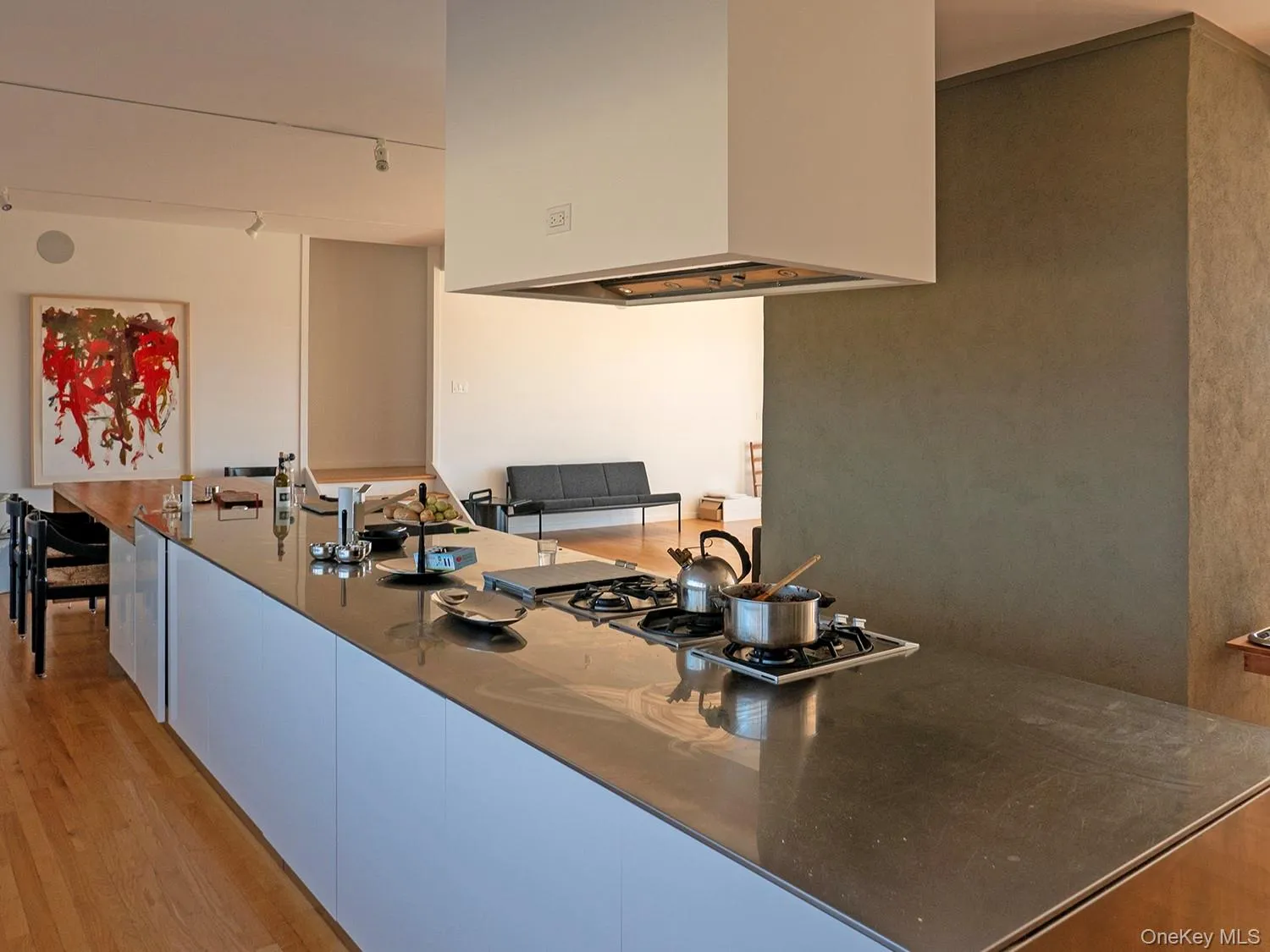 Long, stainless, central kitchen island with gas cooktop burners Long, stainless, central kitchen island with gas cooktop burners