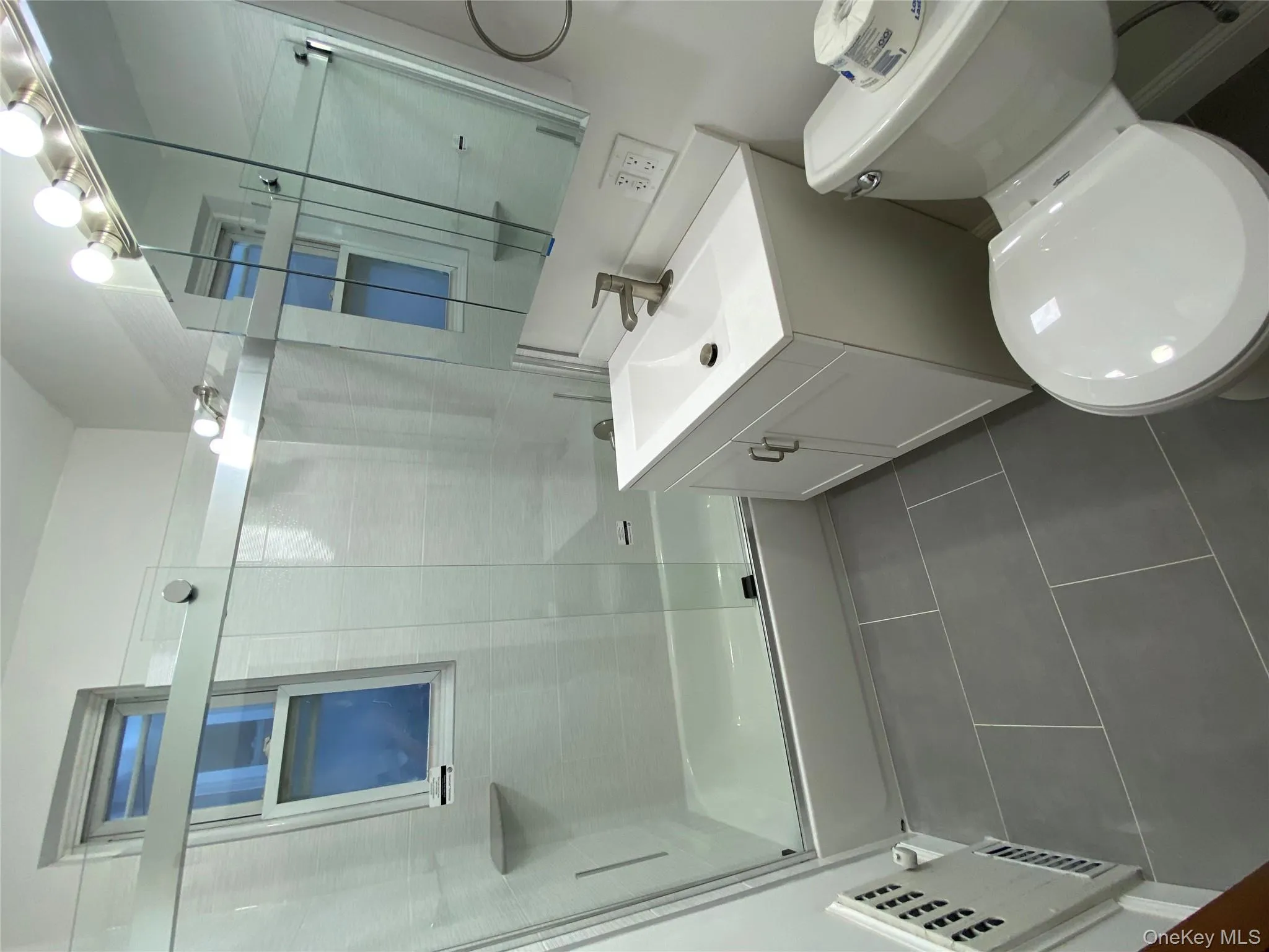 Full bath featuring enclosed tub / shower combo, vanity, and dark tile patterned floors Full bath featuring enclosed tub / shower combo, vanity, and dark tile patterned floors