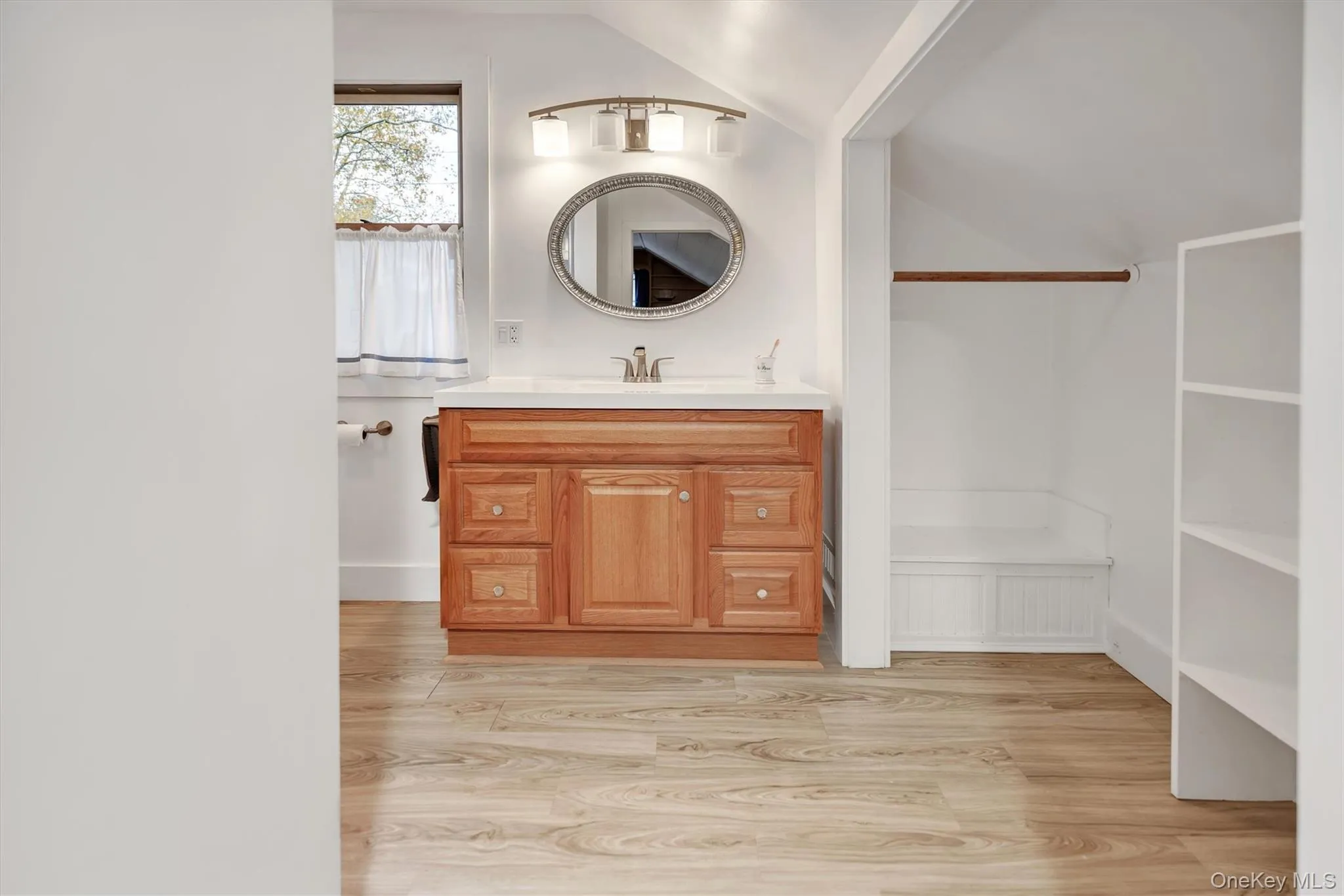 Bathroom featuring vanity, lofted ceiling, and light wood finished floors Bathroom featuring vanity, lofted ceiling, and light wood finished floors