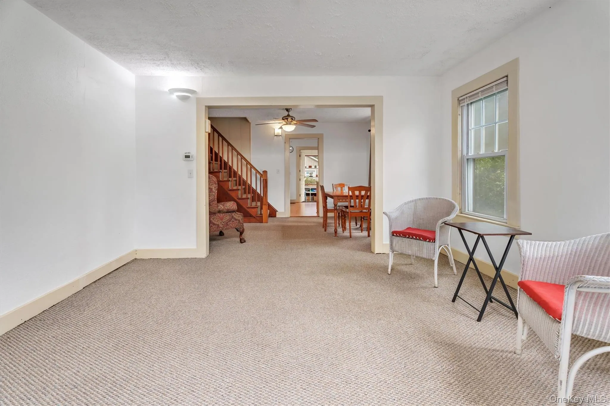 Sitting room featuring carpet floors, a textured ceiling, and stairs Sitting room featuring carpet floors, a textured ceiling, and stairs
