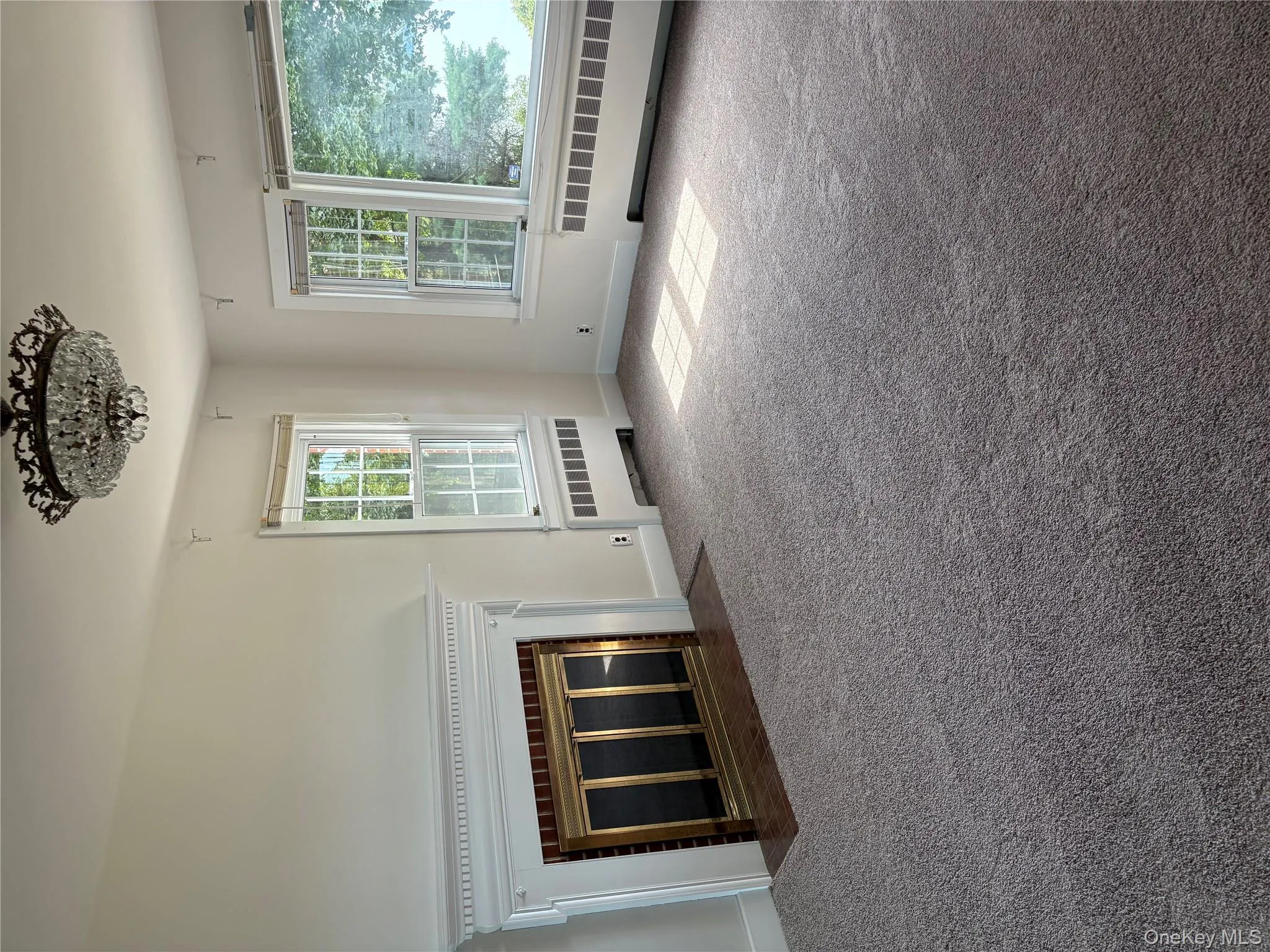 Unfurnished living room with radiator heating unit, carpet flooring, and a brick fireplace Unfurnished living room with radiator heating unit, carpet flooring, and a brick fireplace
