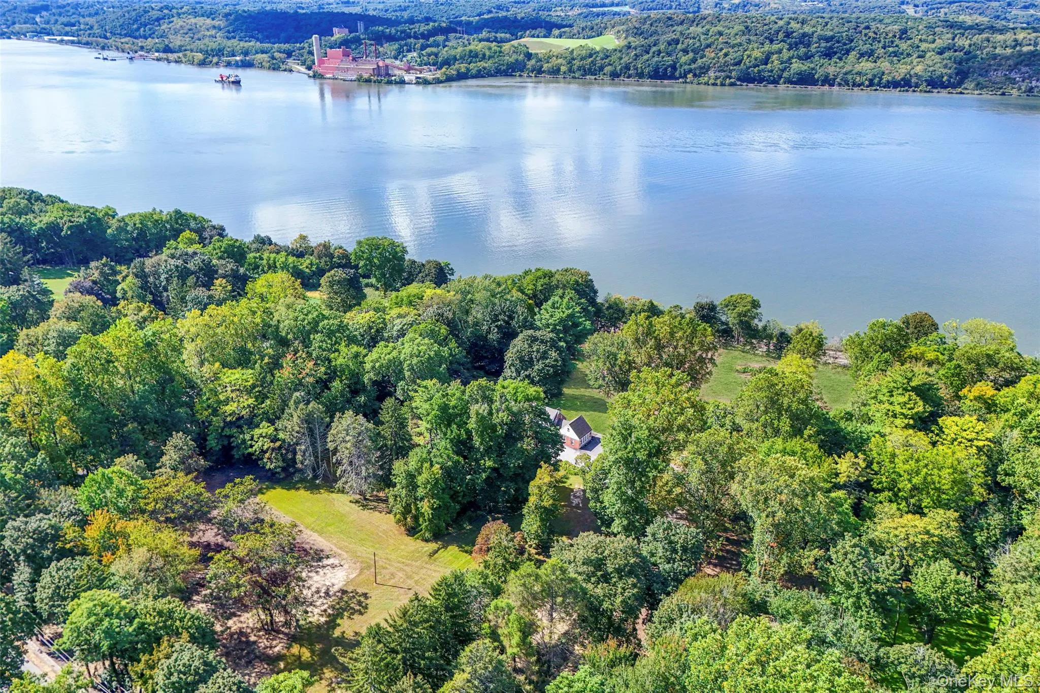 Aerial view of property's location featuring a heavily wooded area and a large body of water Aerial view of property's location featuring a heavily wooded area and a large body of water