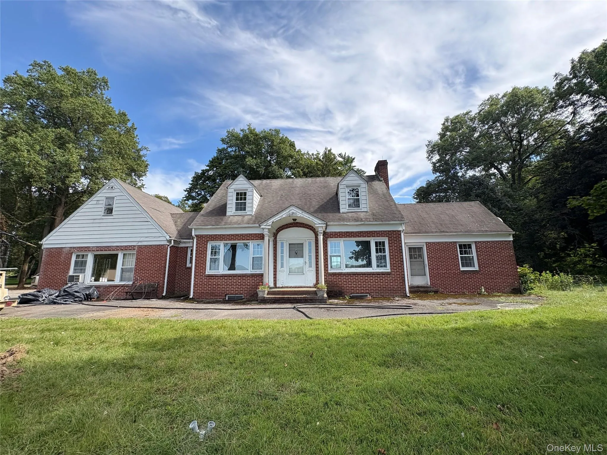Cape cod house featuring brick siding, a front lawn, a chimney, and roof with shingles Cape cod house featuring brick siding, a front lawn, a chimney, and roof with shingles