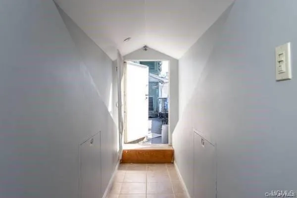 Hallway featuring vaulted ceiling and light tile patterned floors Hallway featuring vaulted ceiling and light tile patterned floors