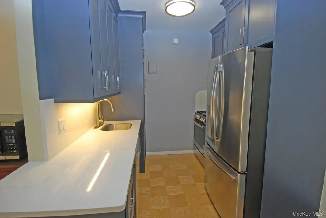 Kitchen featuring appliances with stainless steel finishes, light stone counters, and blue cabinetry Kitchen featuring appliances with stainless steel finishes, light stone counters, and blue cabinetry