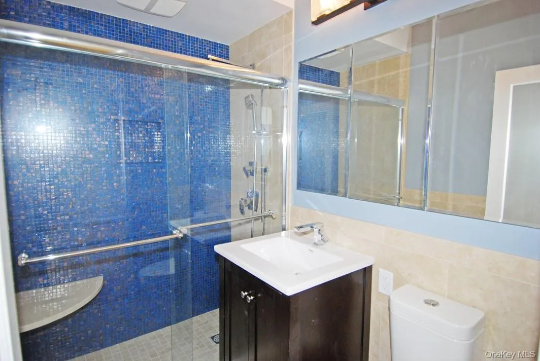 Full bathroom with a shower stall, tile walls, and vanity Full bathroom with a shower stall, tile walls, and vanity