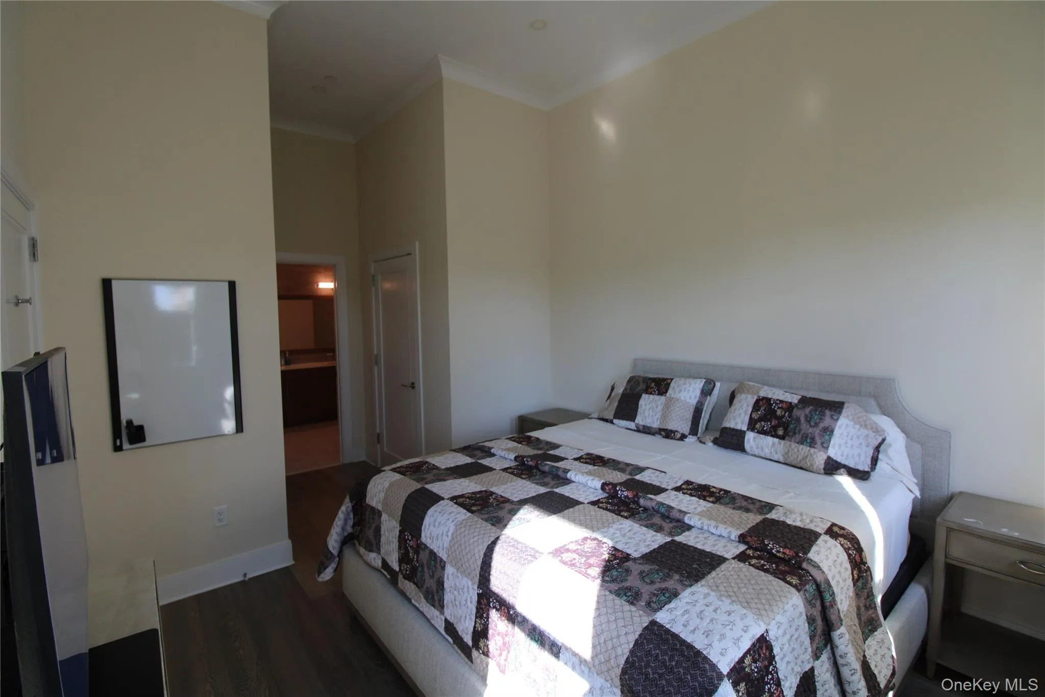 Bedroom with dark wood-type flooring, crown molding, ensuite bathroom, and a towering ceiling Bedroom with dark wood-type flooring, crown molding, ensuite bathroom, and a towering ceiling