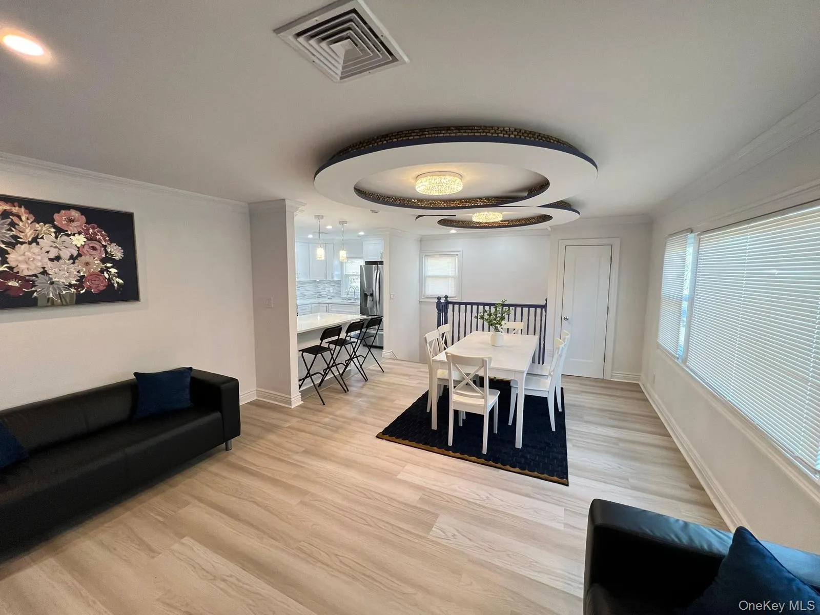 Dining room with ornamental molding, light wood-type flooring, and a tray ceiling Dining room with ornamental molding, light wood-type flooring, and a tray ceiling
