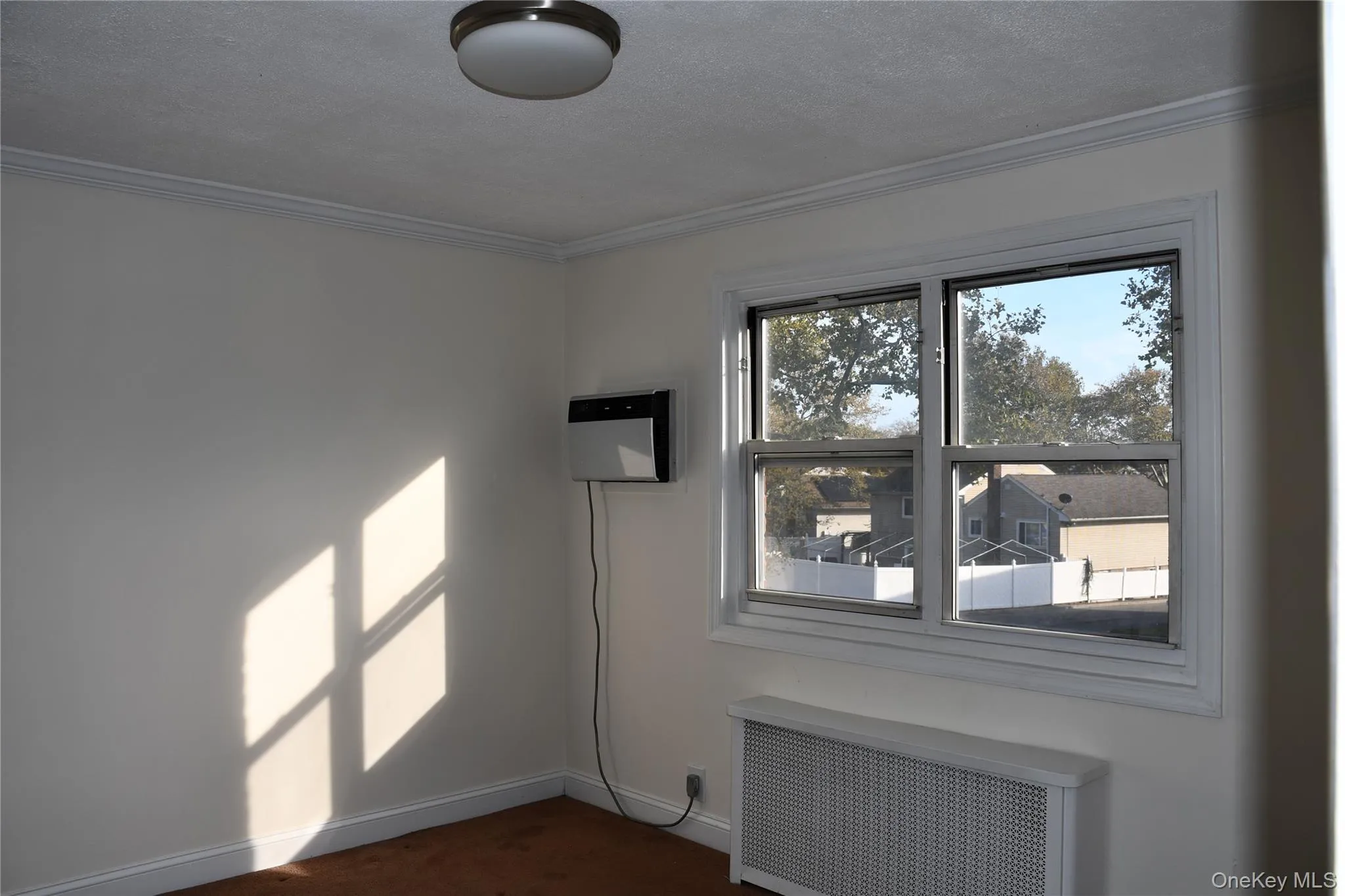 Spare room with radiator, a textured ceiling, crown molding, a wall unit AC, and dark carpet Spare room with radiator, a textured ceiling, crown molding, a wall unit AC, and dark carpet