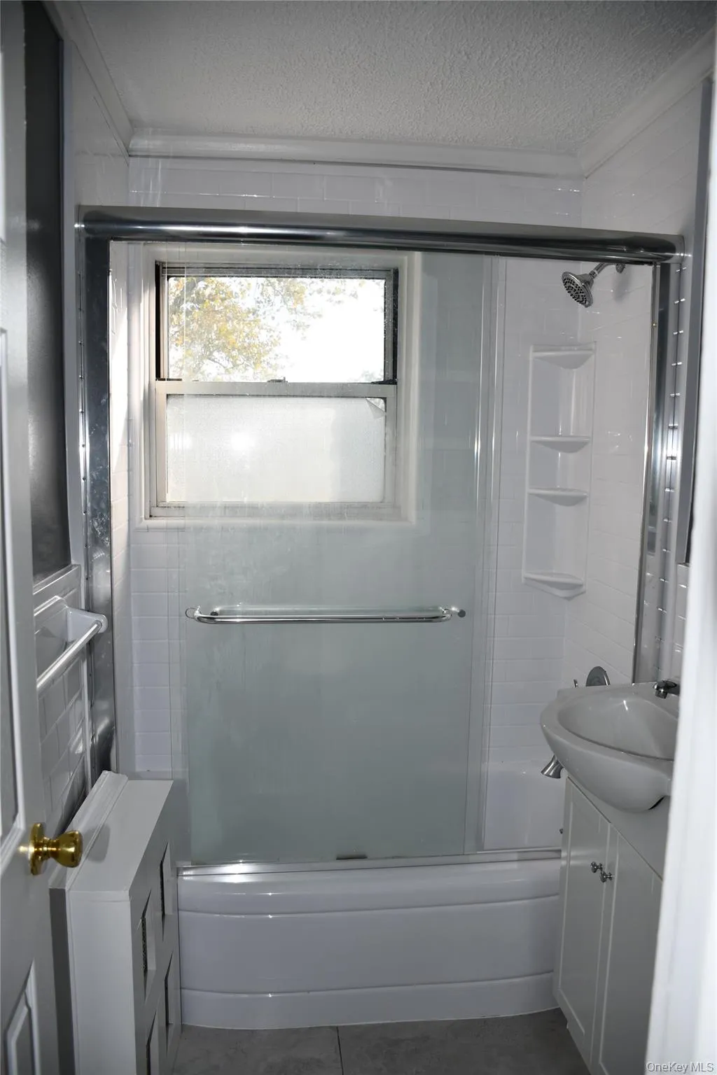 Bathroom featuring enclosed tub / shower combo, vanity, dark tile patterned flooring, a textured ceiling, and ornamental molding Bathroom featuring enclosed tub / shower combo, vanity, dark tile patterned flooring, a textured ceiling, and ornamental molding