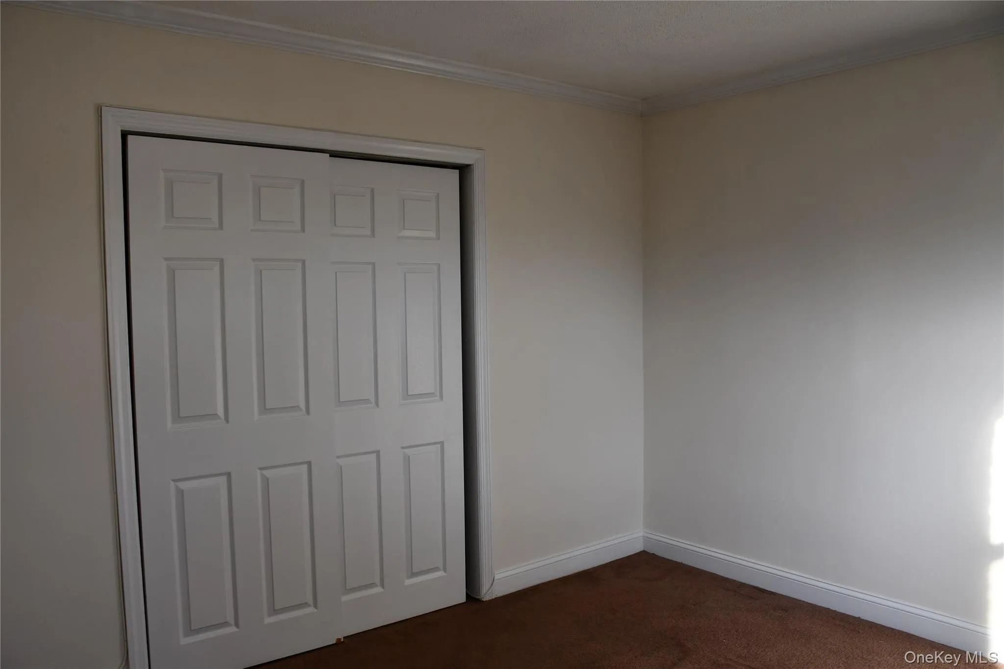 Unfurnished bedroom with dark carpet, a closet, and crown molding Unfurnished bedroom with dark carpet, a closet, and crown molding