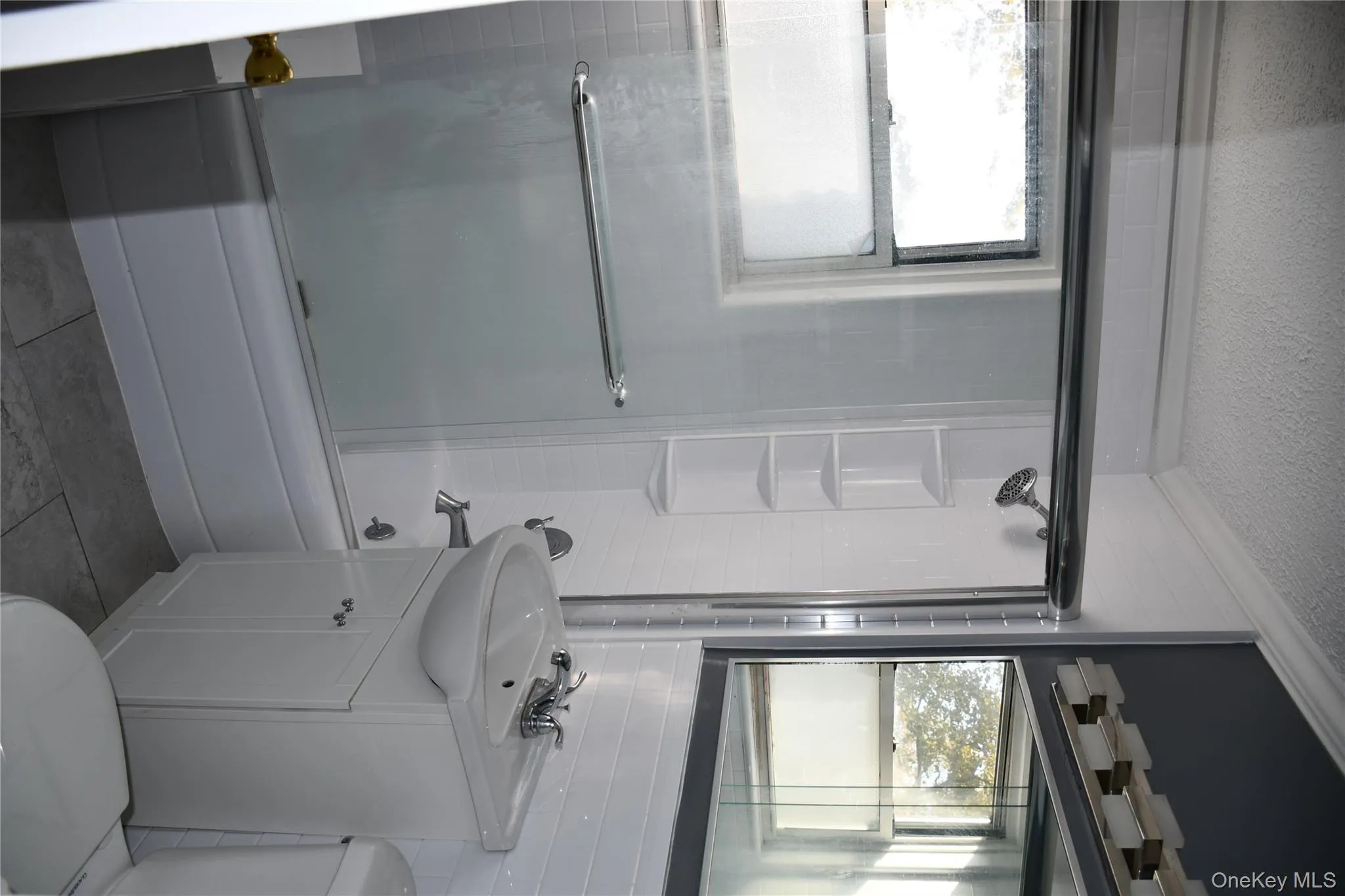 Bathroom with enclosed tub / shower combo, vanity, a textured ceiling, light tile patterned floors, and crown molding Bathroom with enclosed tub / shower combo, vanity, a textured ceiling, light tile patterned floors, and crown molding