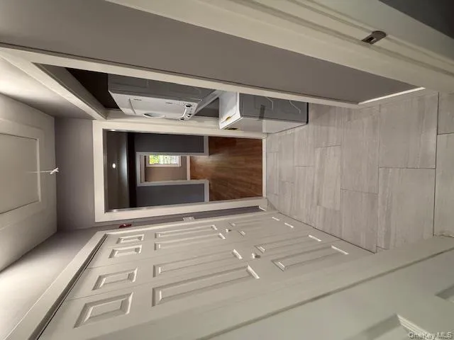Corridor with stacked washing machine and dryer, attic access, and light wood-type flooring Corridor with stacked washing machine and dryer, attic access, and light wood-type flooring