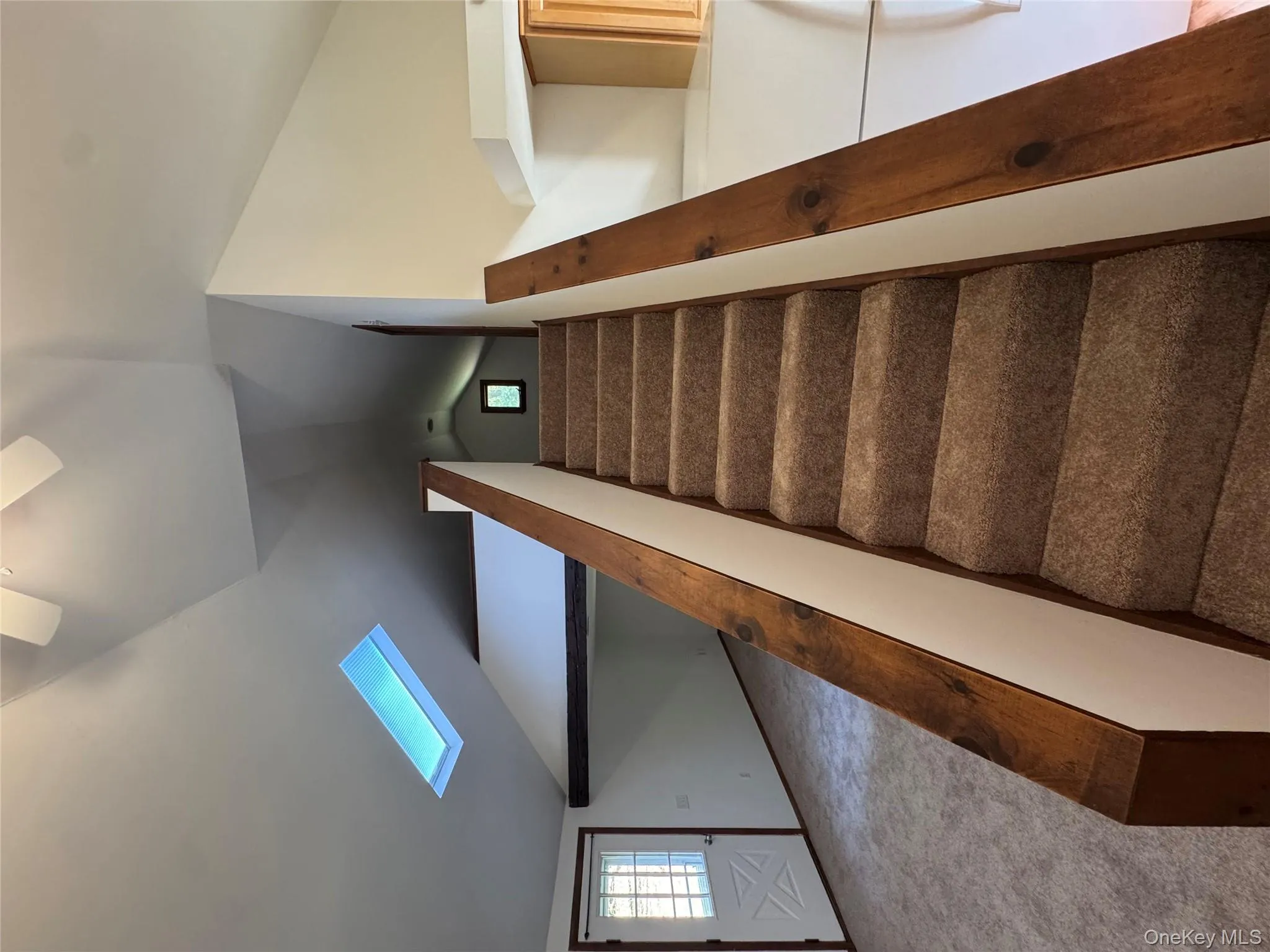 Stairway featuring a skylight, vaulted ceiling, and carpet floors Stairway featuring a skylight, vaulted ceiling, and carpet floors