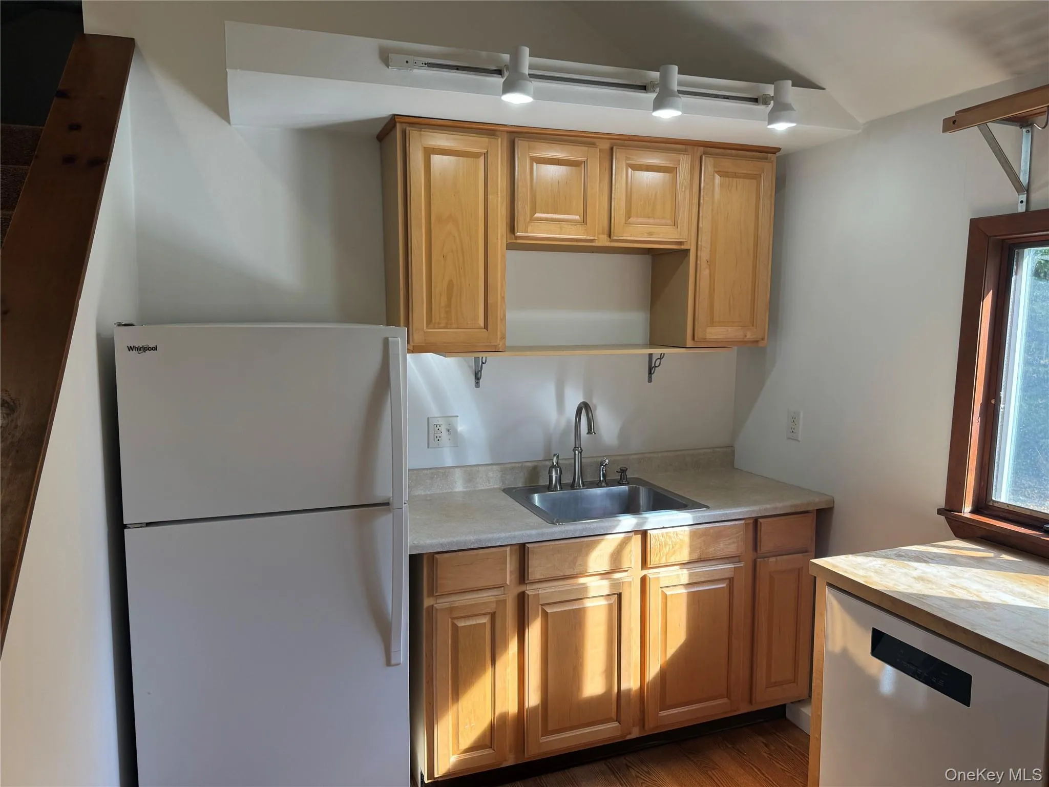 Kitchen featuring freestanding refrigerator, dishwasher, wood finished floors, and brown cabinetry Kitchen featuring freestanding refrigerator, dishwasher, wood finished floors, and brown cabinetry