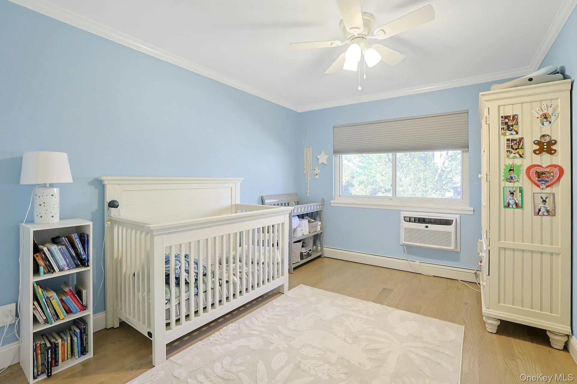 Bedroom with ornamental molding, light wood-style floors, a baseboard radiator, and ceiling fan Bedroom with ornamental molding, light wood-style floors, a baseboard radiator, and ceiling fan