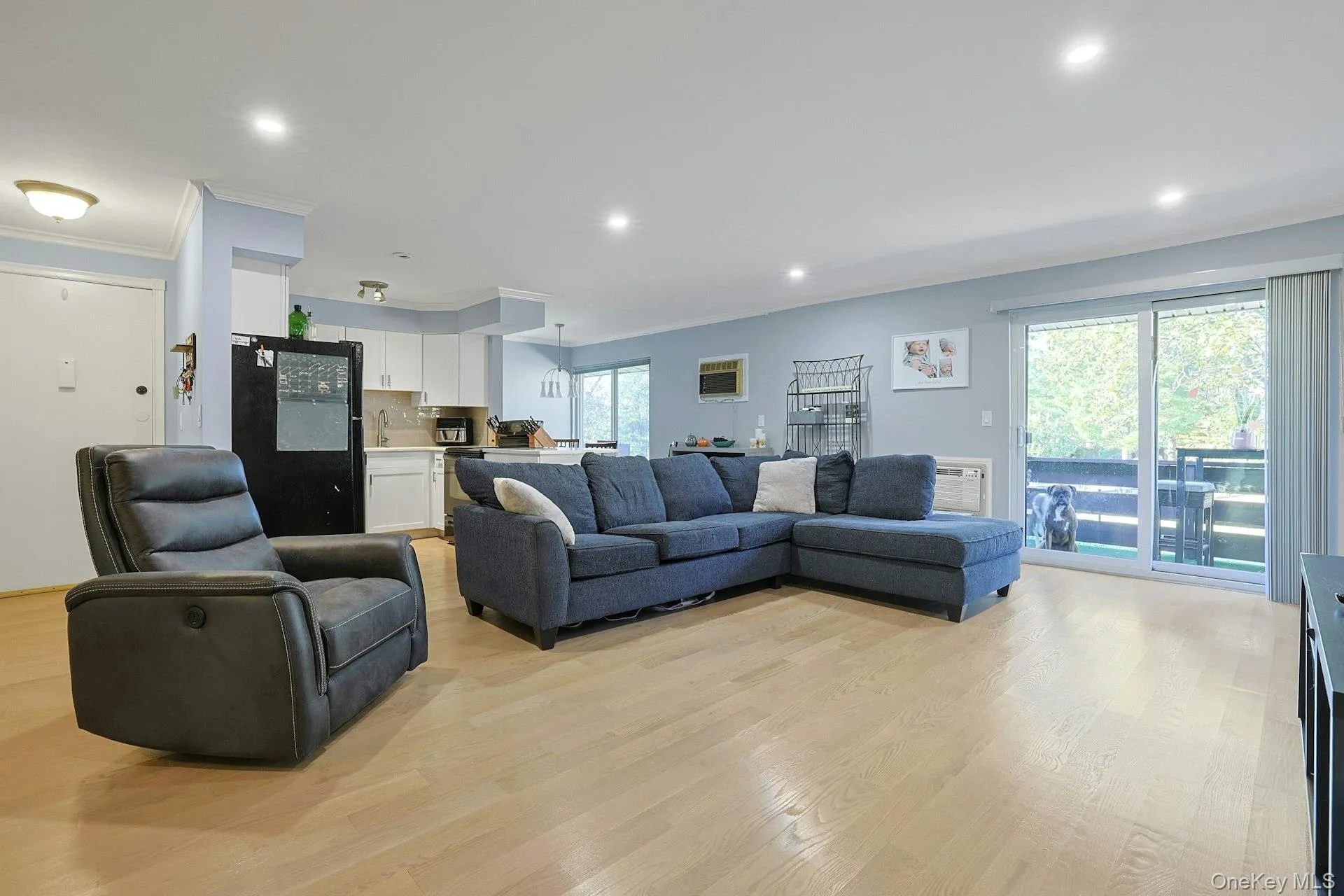 Living room featuring ornamental molding, light wood-type flooring, recessed lighting, and a wall unit AC Living room featuring ornamental molding, light wood-type flooring, recessed lighting, and a wall unit AC