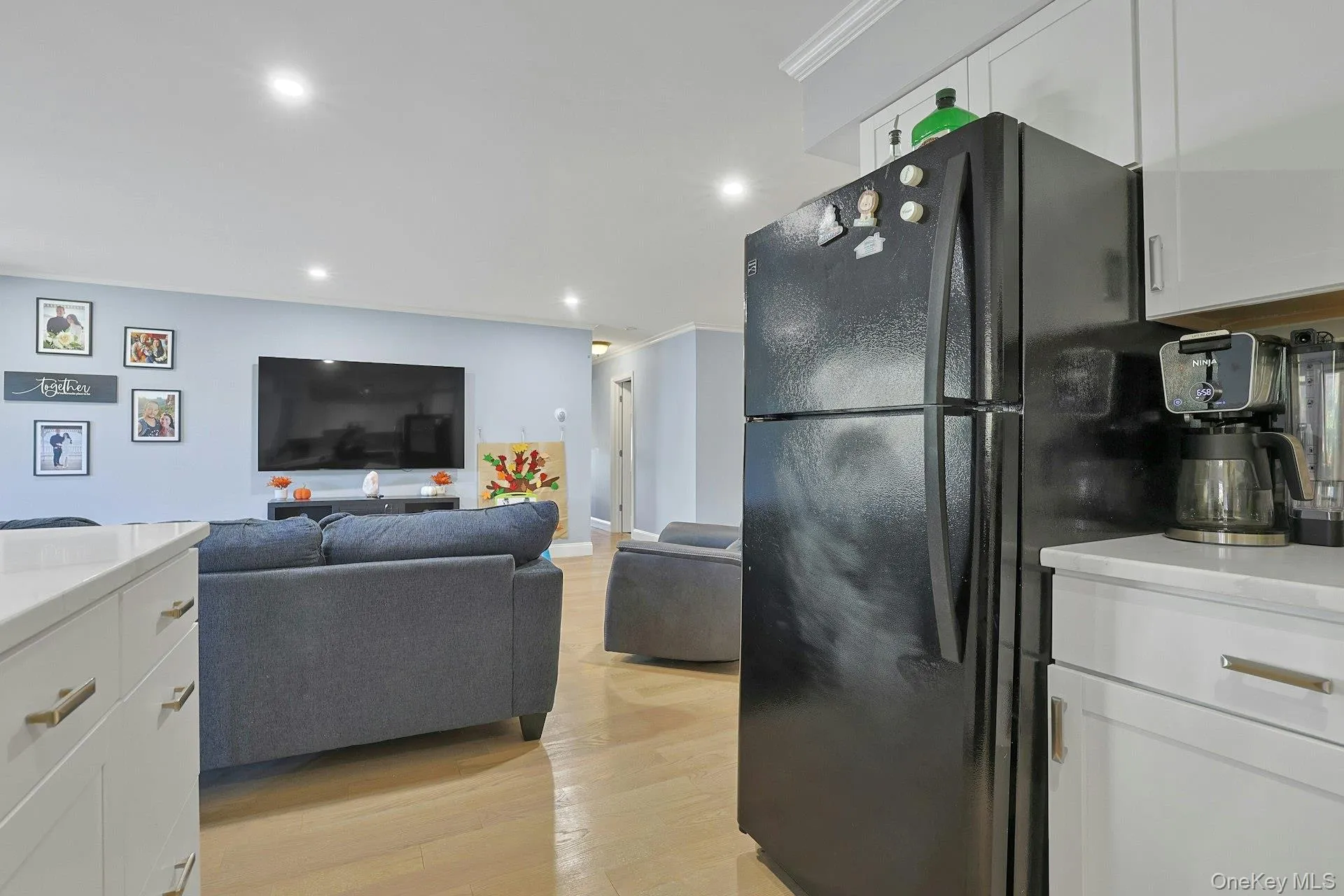 Kitchen with white cabinetry, freestanding refrigerator, light stone countertops, recessed lighting, and light wood-style floors Kitchen with white cabinetry, freestanding refrigerator, light stone countertops, recessed lighting, and light wood-style floors