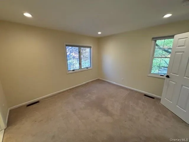 Empty room featuring recessed lighting, healthy amount of natural light, and light colored carpet Empty room featuring recessed lighting, healthy amount of natural light, and light colored carpet