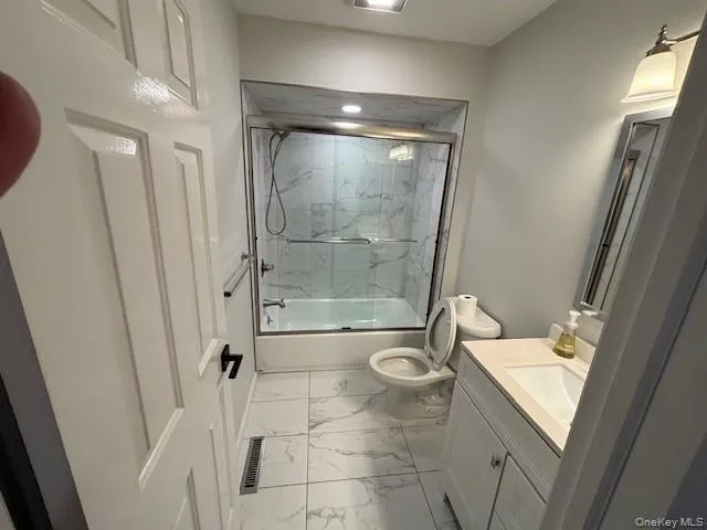Bathroom featuring enclosed tub / shower combo, light marble finish flooring, and vanity Bathroom featuring enclosed tub / shower combo, light marble finish flooring, and vanity